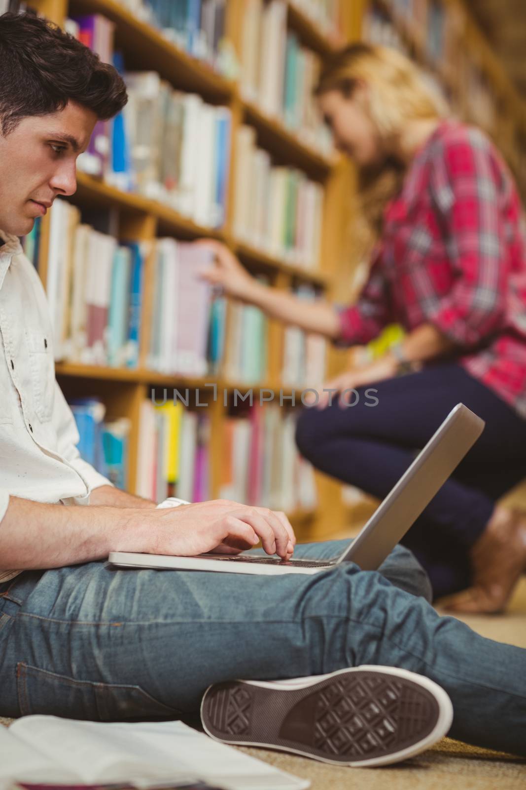 Student using laptop on floor in library