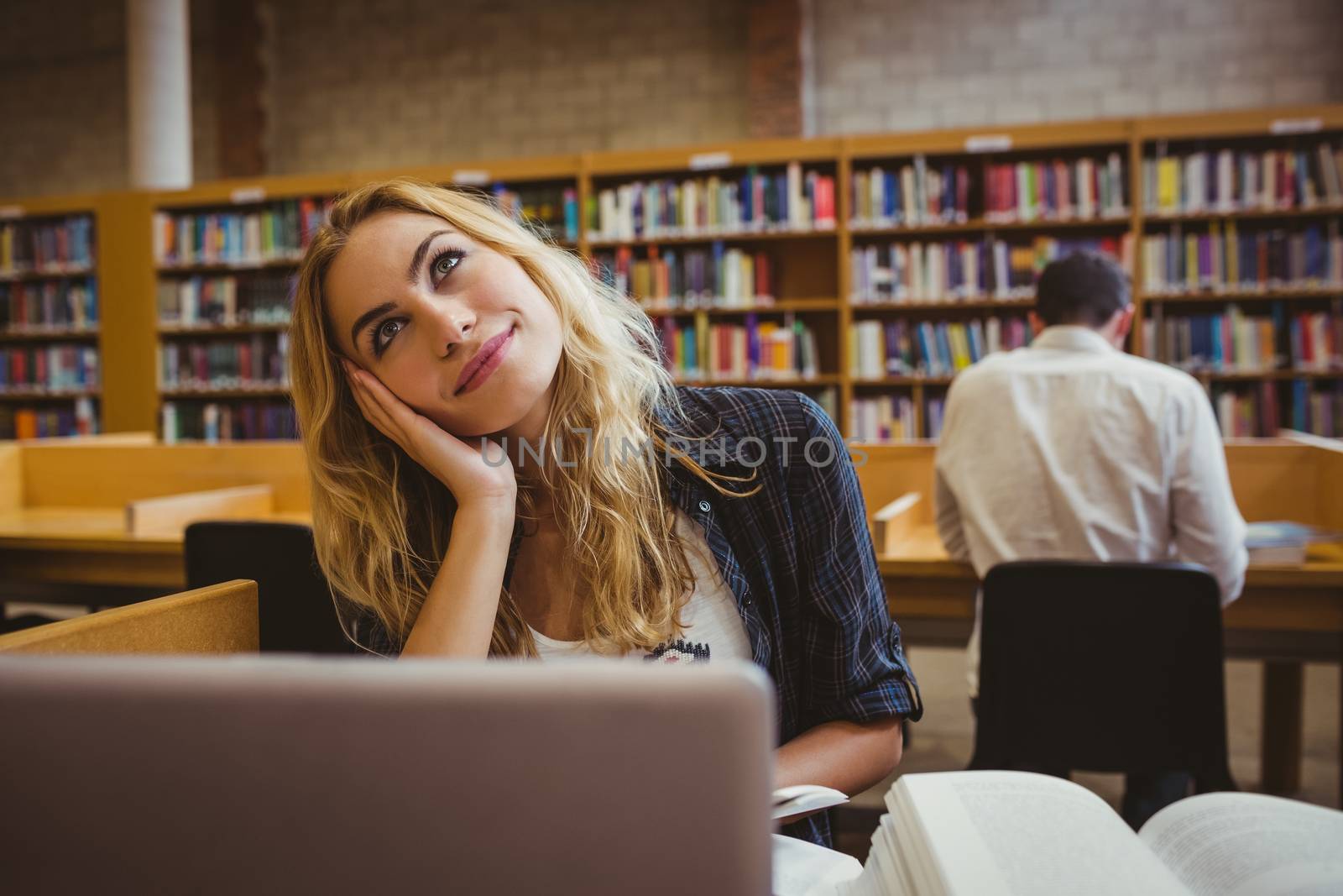 Smiling student working while using her laptop in library