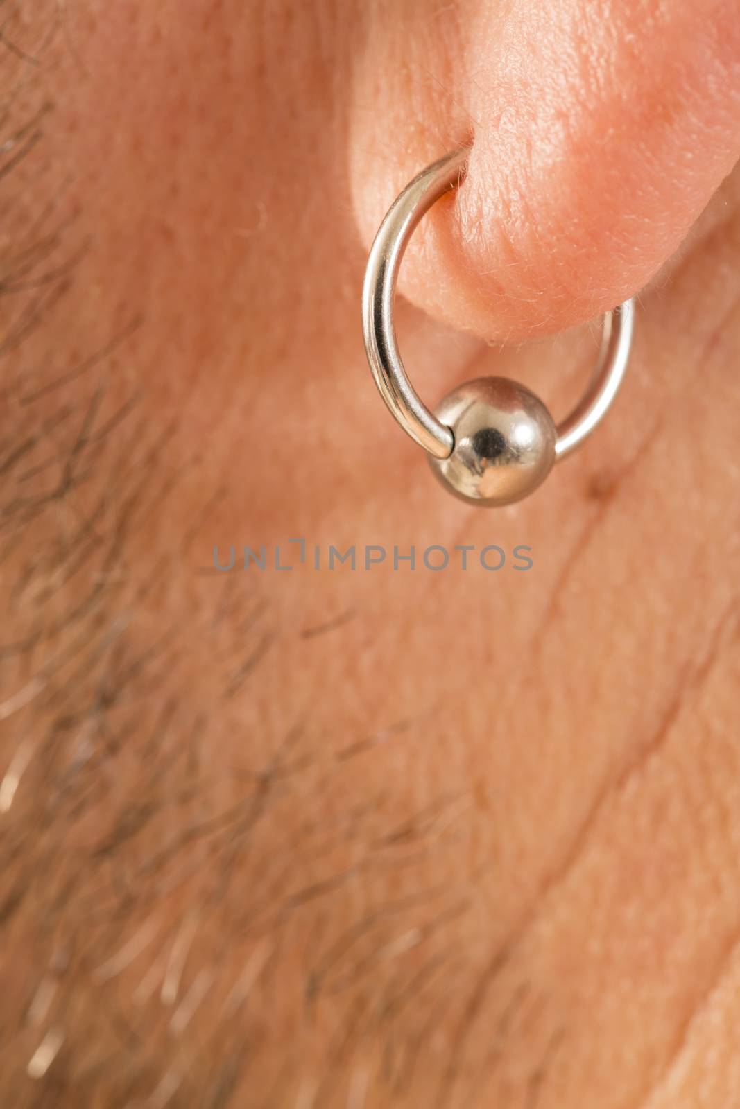 pierced ear of a mature man close-up short beard