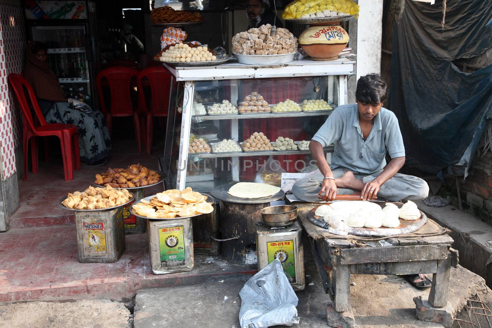 Vendor sits in lotus position while sells goods in Indian shop. January 17, 2009. Sonakhali, West Bengal, India.