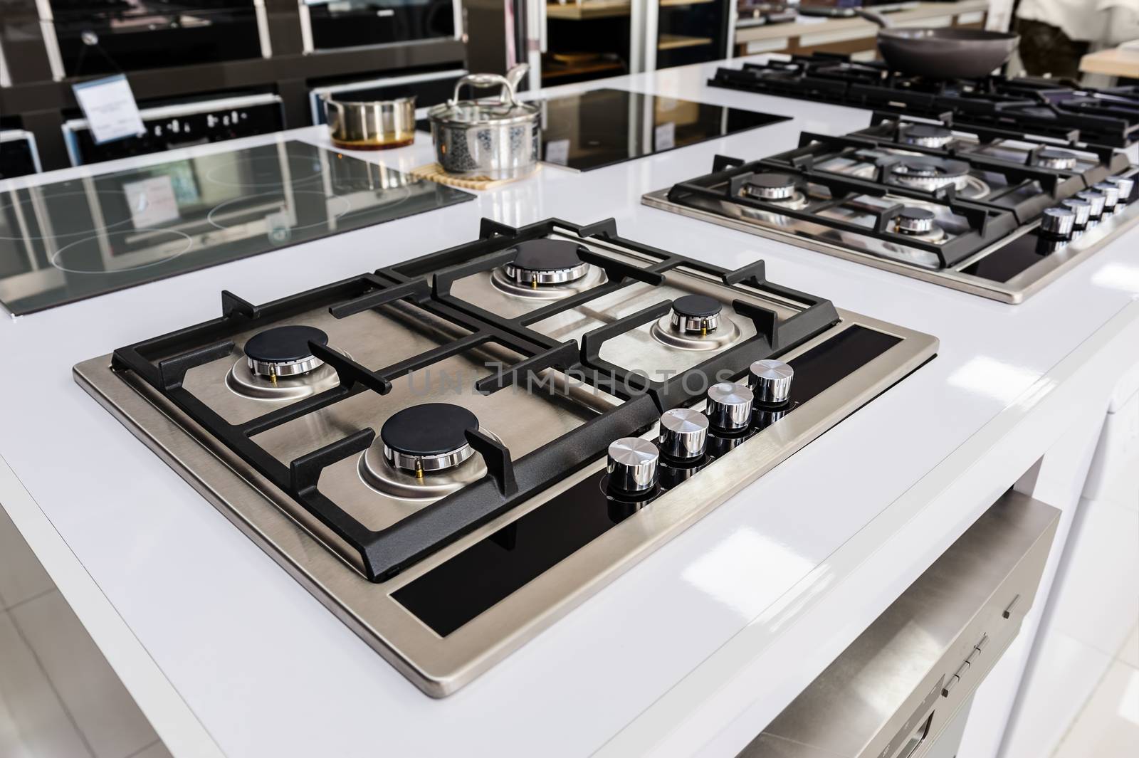 Rows of gas stoves with stainless tray selling in appliance retail store