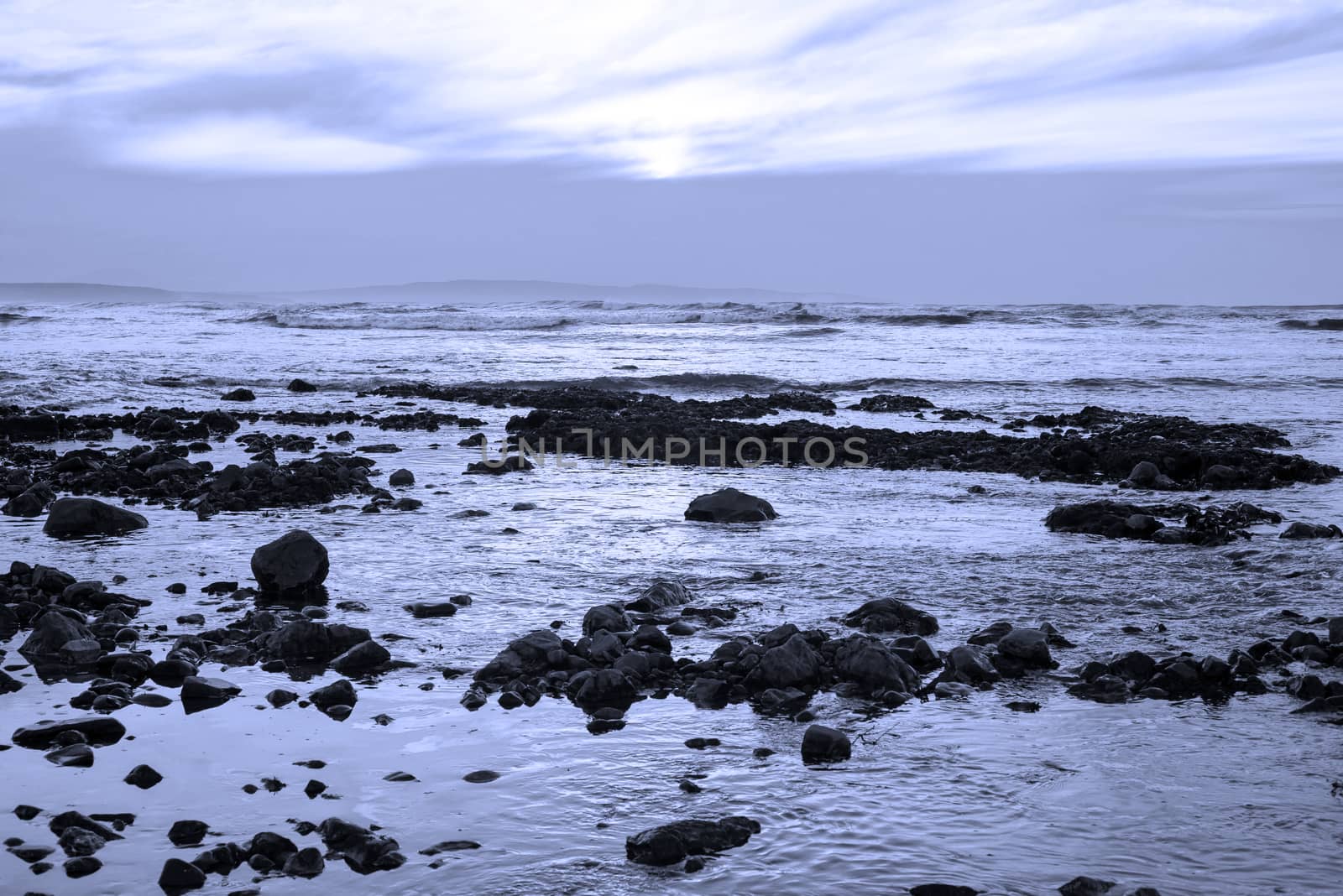 blue rocks at rocky grey beach by morrbyte