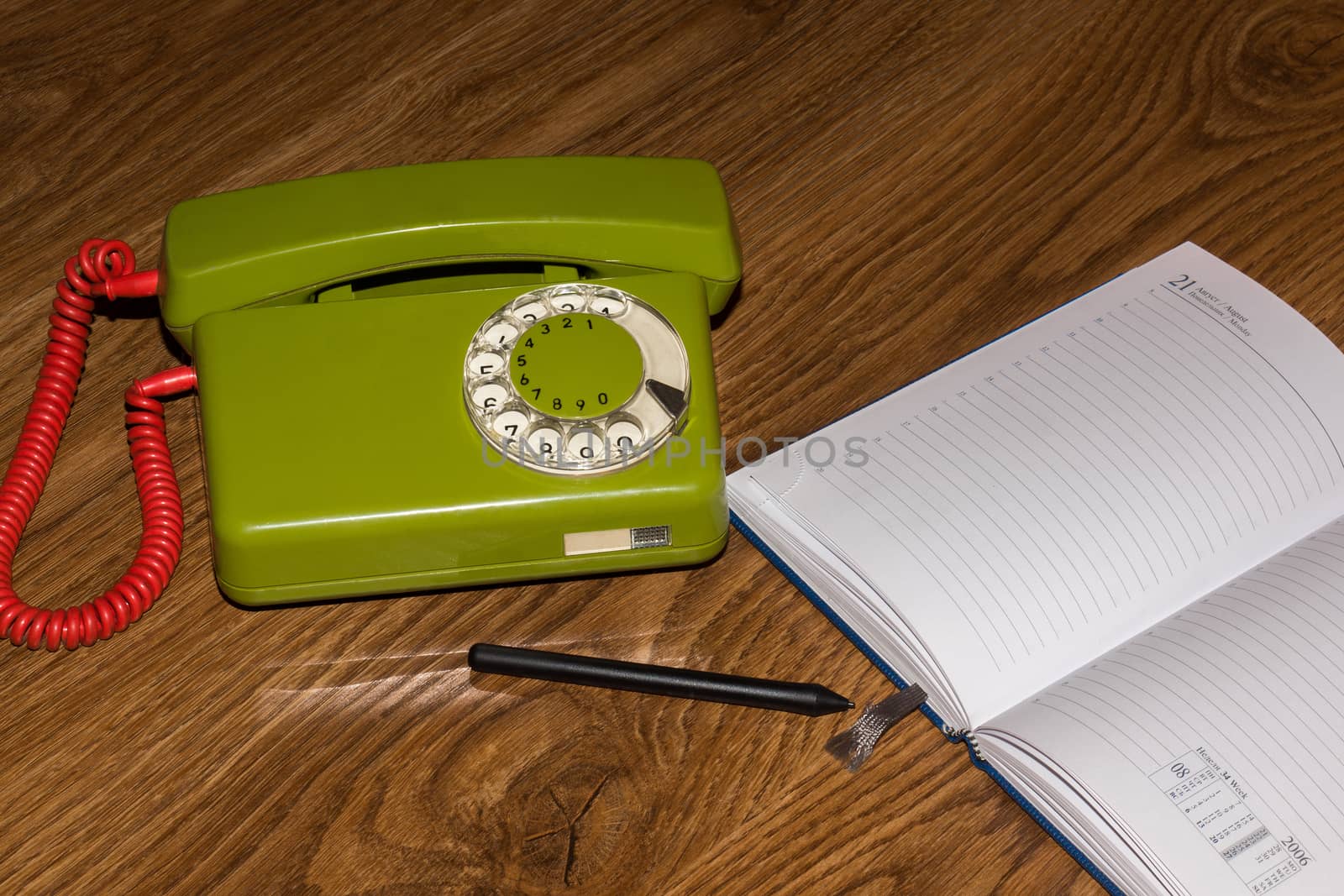 The photo depicts a landline phone with a notebook