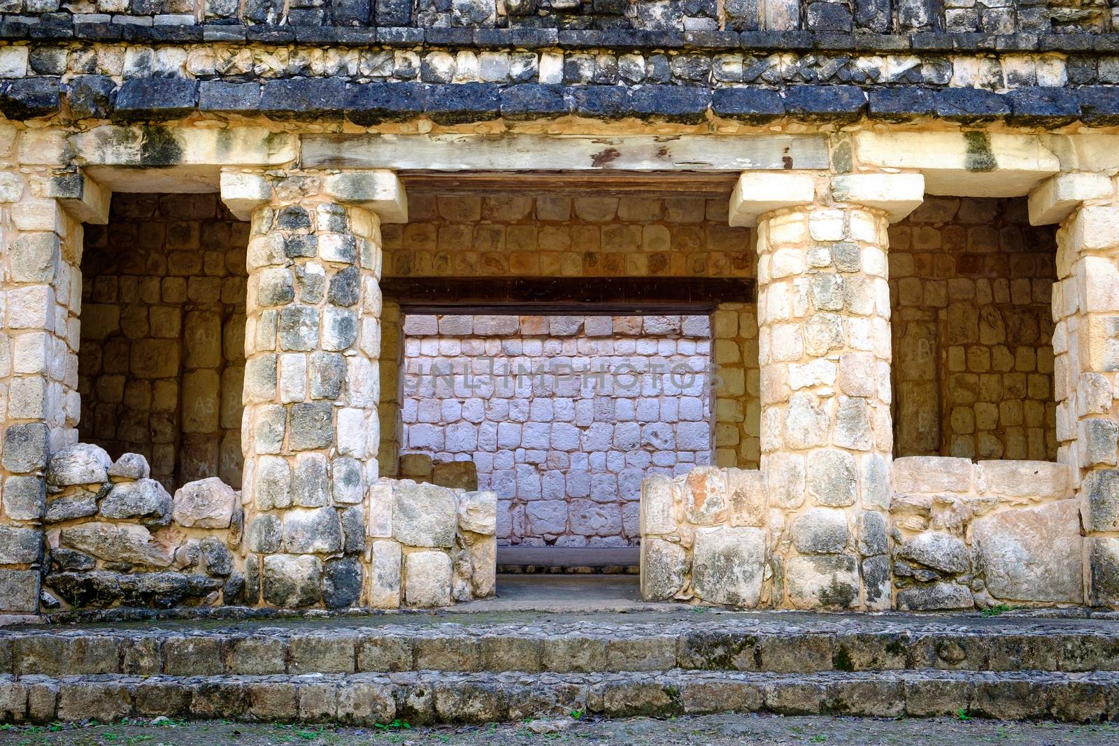 Detail of ancient stone wall ruins with pillars and windows, Uxmal, Mexico