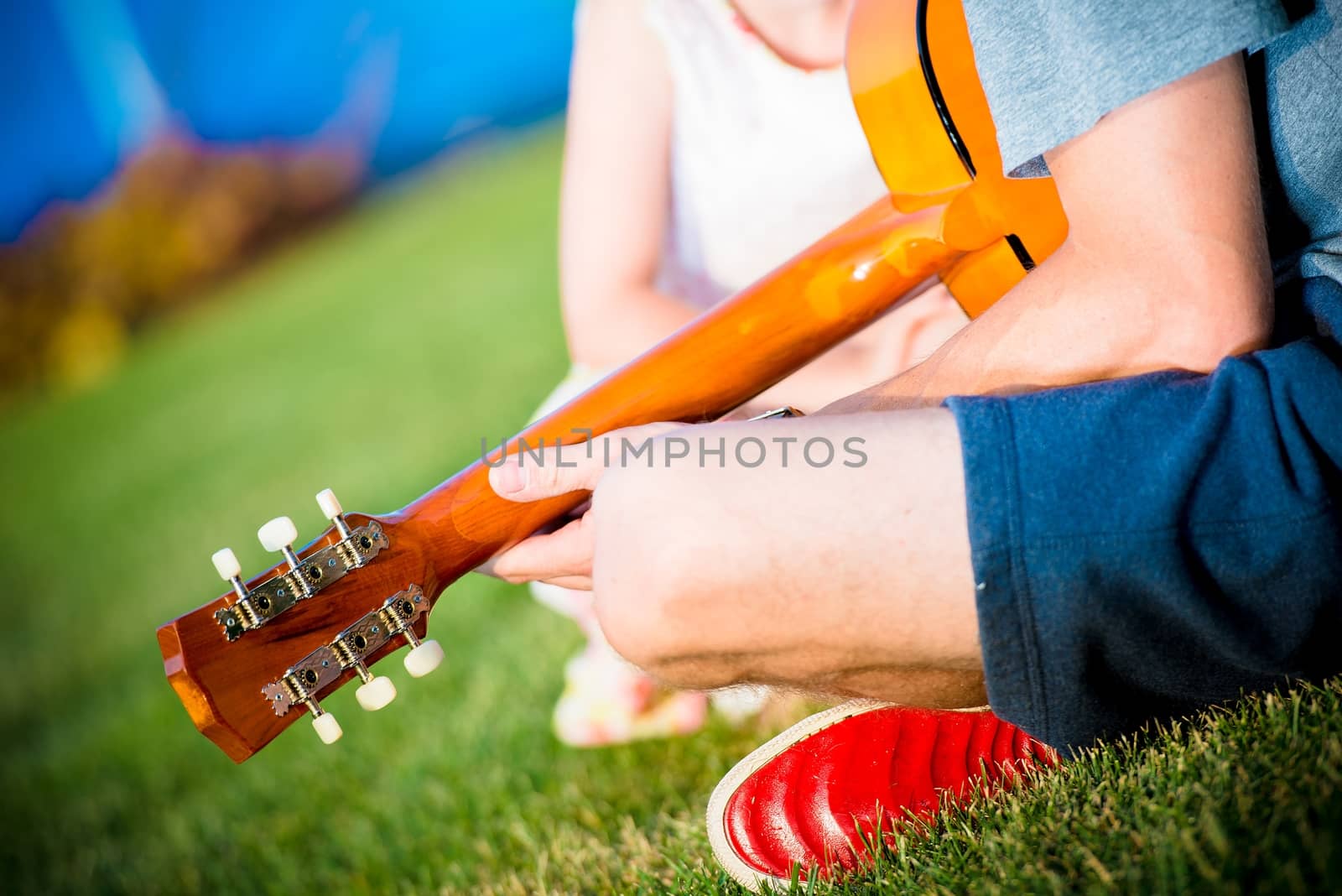 Dad Playing Guitar For His Daughter While Seating on the Backyard Grass. Backyard Fun Time.