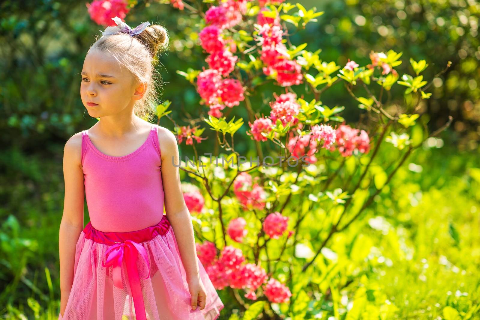 Caucasian Girl in Pink Dress Posing in the Pink Blossom Summer Garden