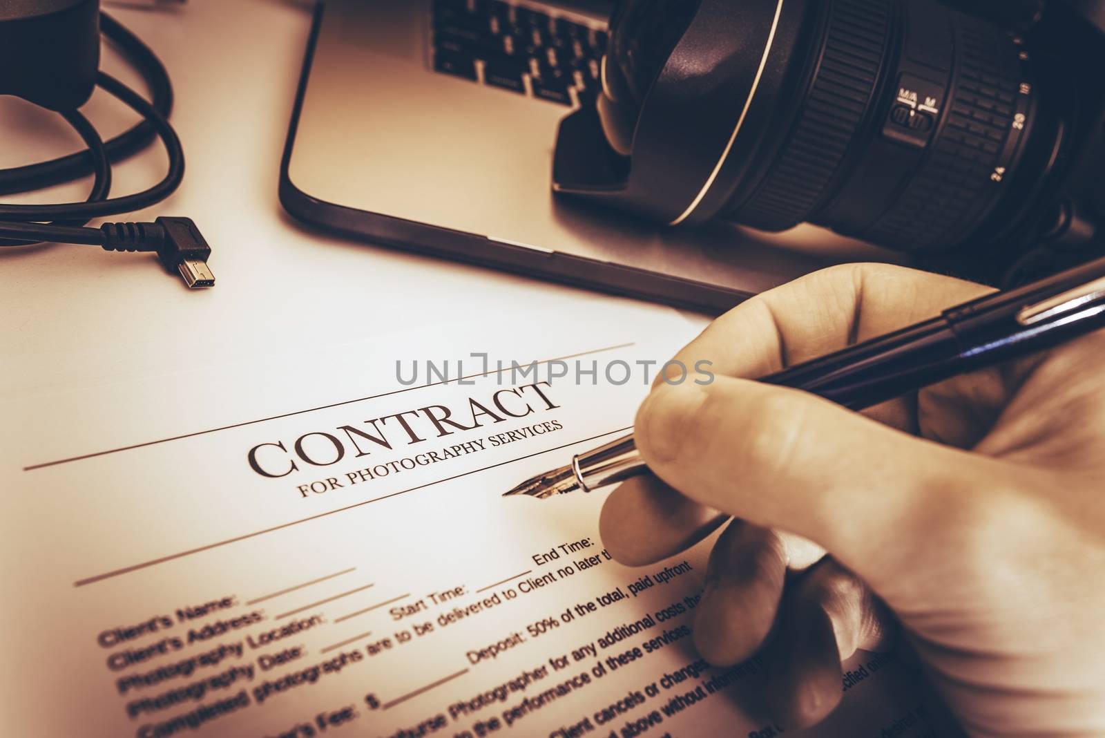 Photography Services Contract Preparing by Professional Photographer on His Work Desk.