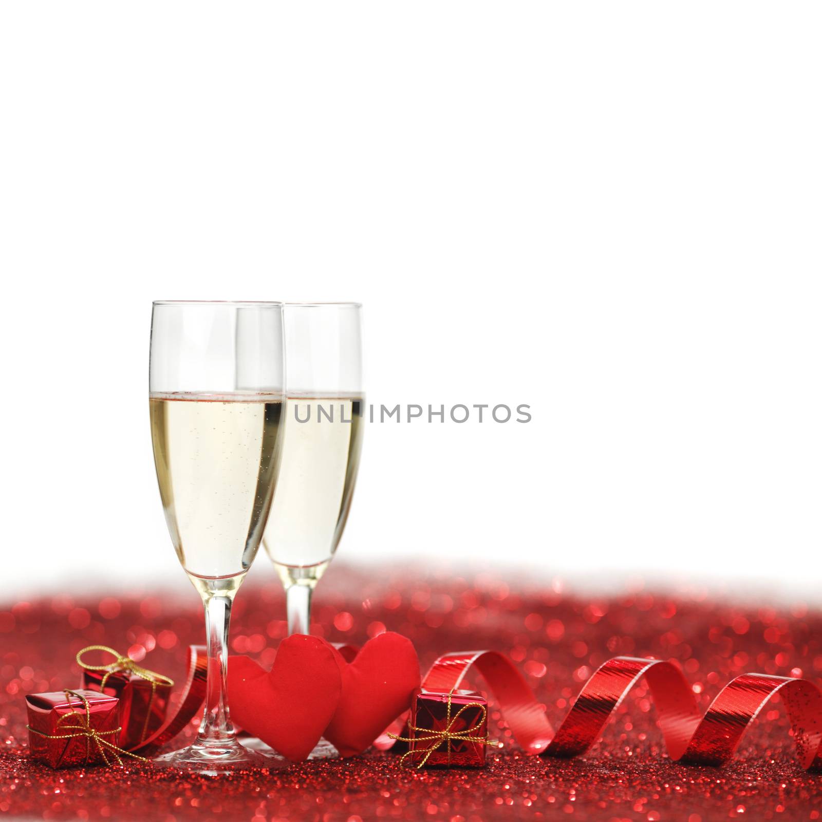 Glasses with Champagne and handmade hearts on red glitters isolated on white background