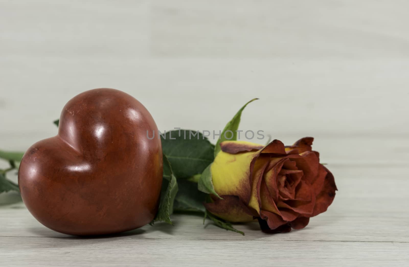 red rose with heart shape on wooden background for mothers day or valentines