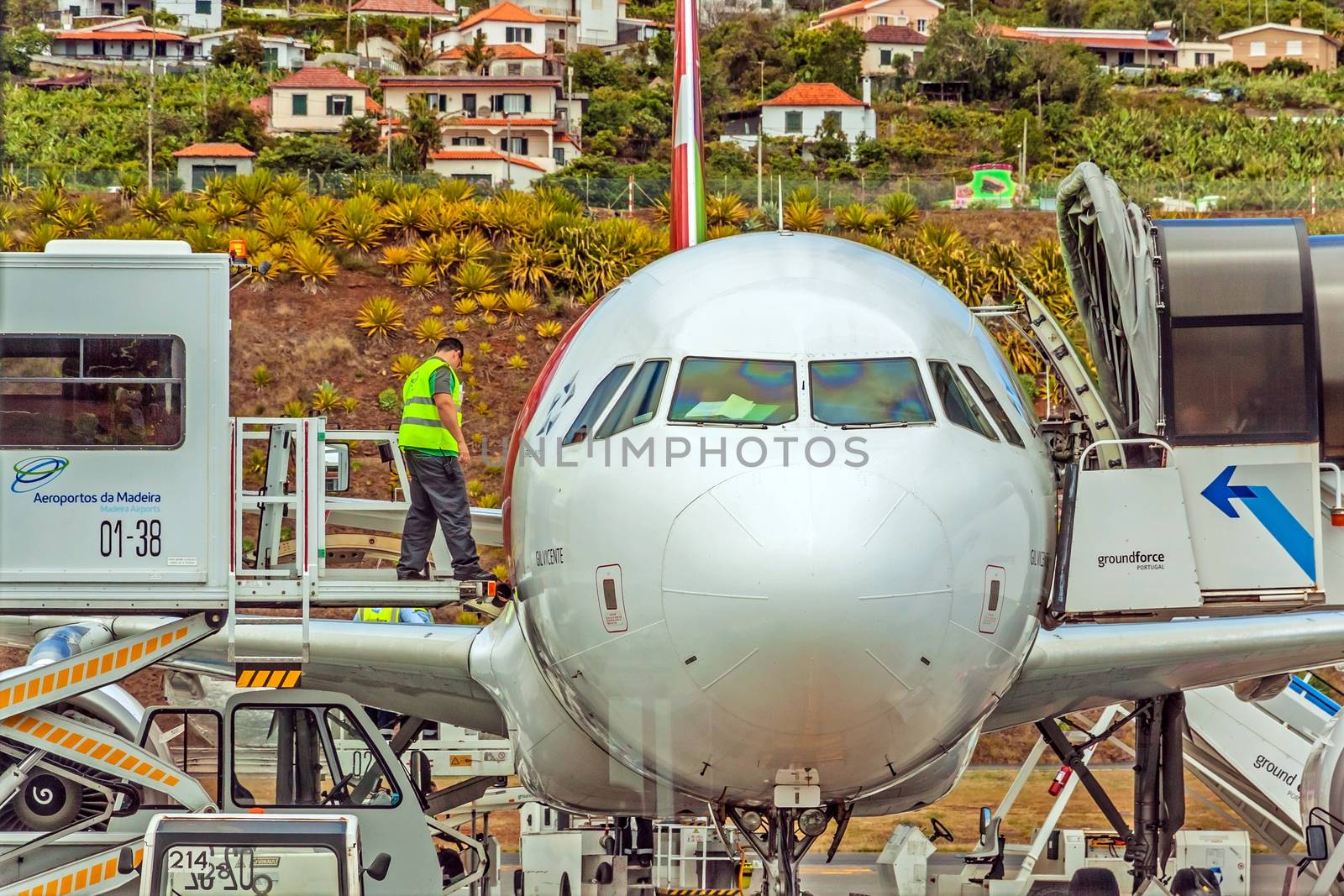 Funchal, Madeira, Portugal - May 30, 2013: At the airport of Madeira (Aeroporto Madeira) - an airplane Airbus A320 from TAP Portugal Airline in parking position. Ground force stuff at work.