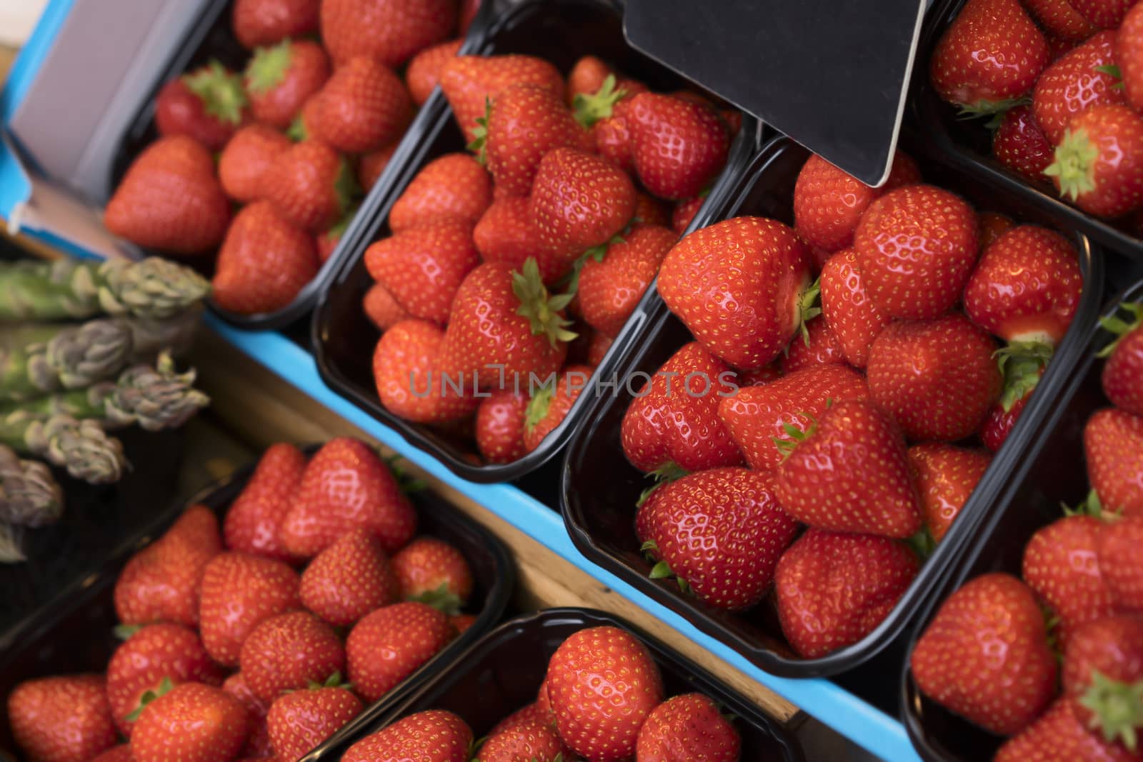 Baskets of fresh bright red seasonal strawberries on market stand for sale