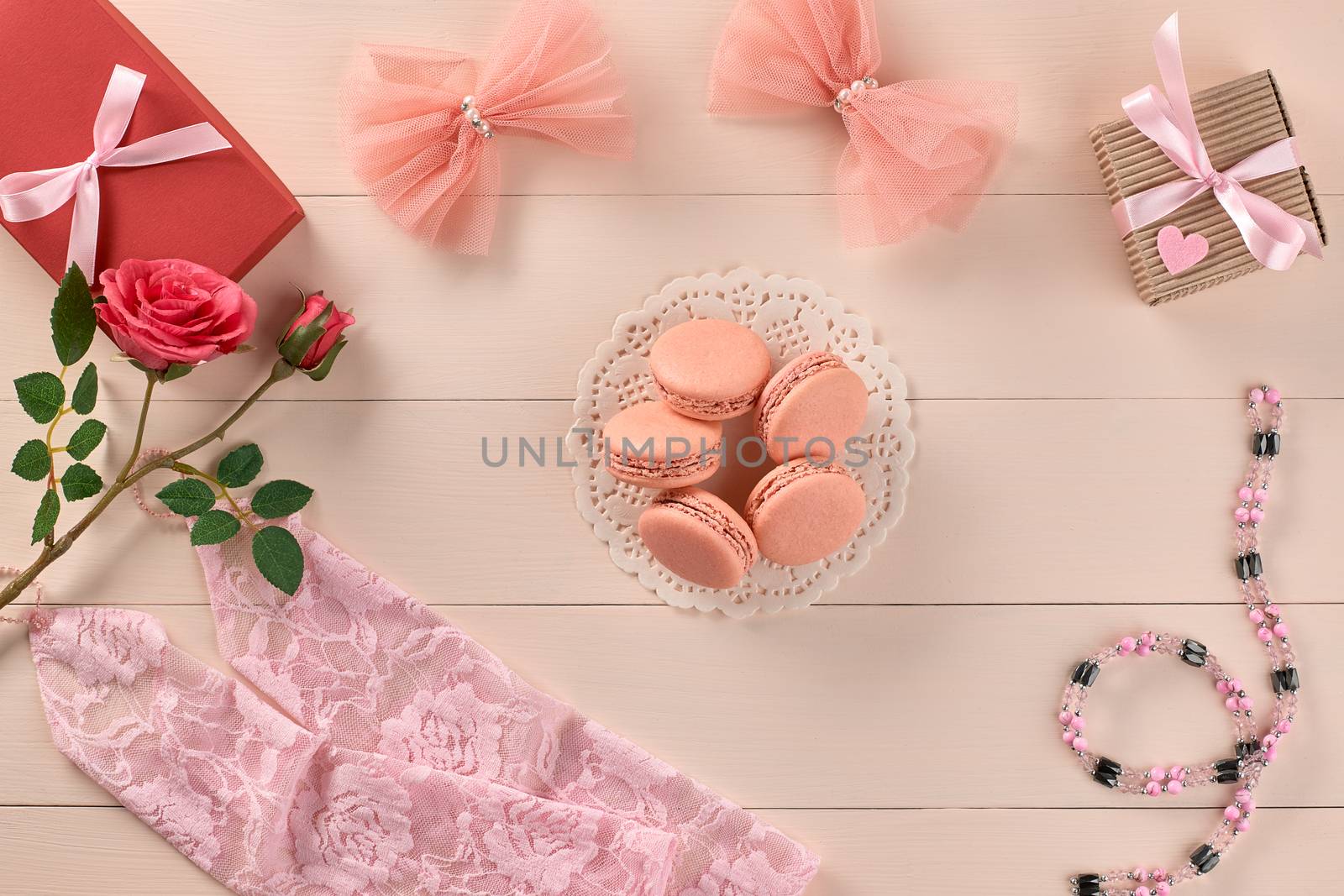 Overhead woman essentials fashion wedding accessories set. Lace gloves, macarons, gift boxes, necklace and roses. Creative bride set, vanilla wooden background. Romantic modern, still life. Top view