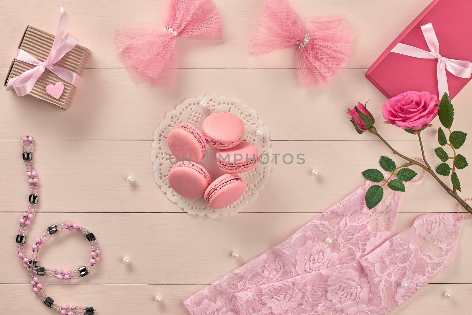 Overhead woman essentials fashion wedding accessories set. Lace gloves, macarons, gift boxes, necklace and roses. Creative bride set, vanilla wooden background. Romantic modern, still life. Top view