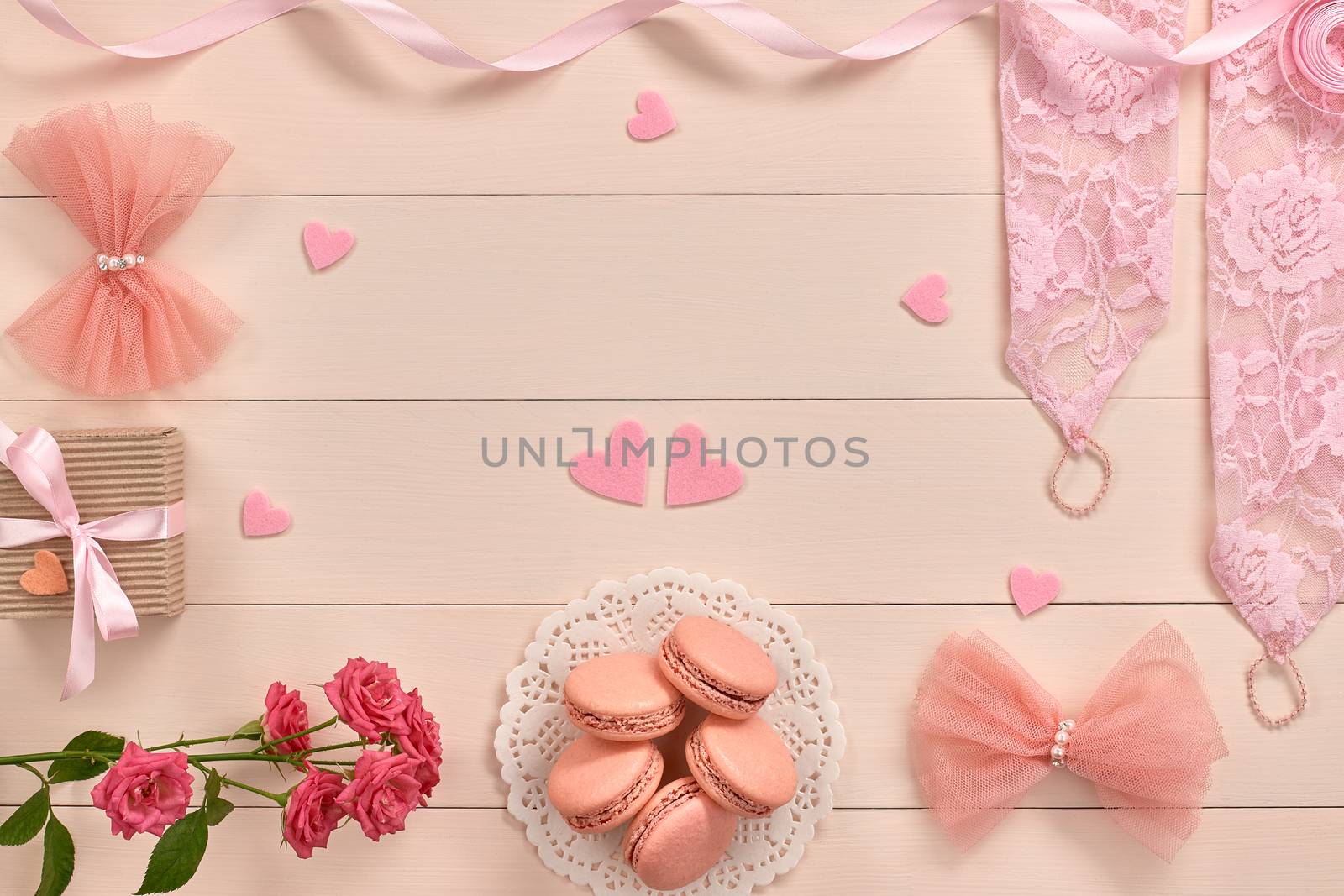 Overhead woman essentials fashion wedding accessories set. Lace gloves, macarons, gift box, hearts love and roses. Creative bride set, vanilla wooden background. Romantic modern, still life. Top view