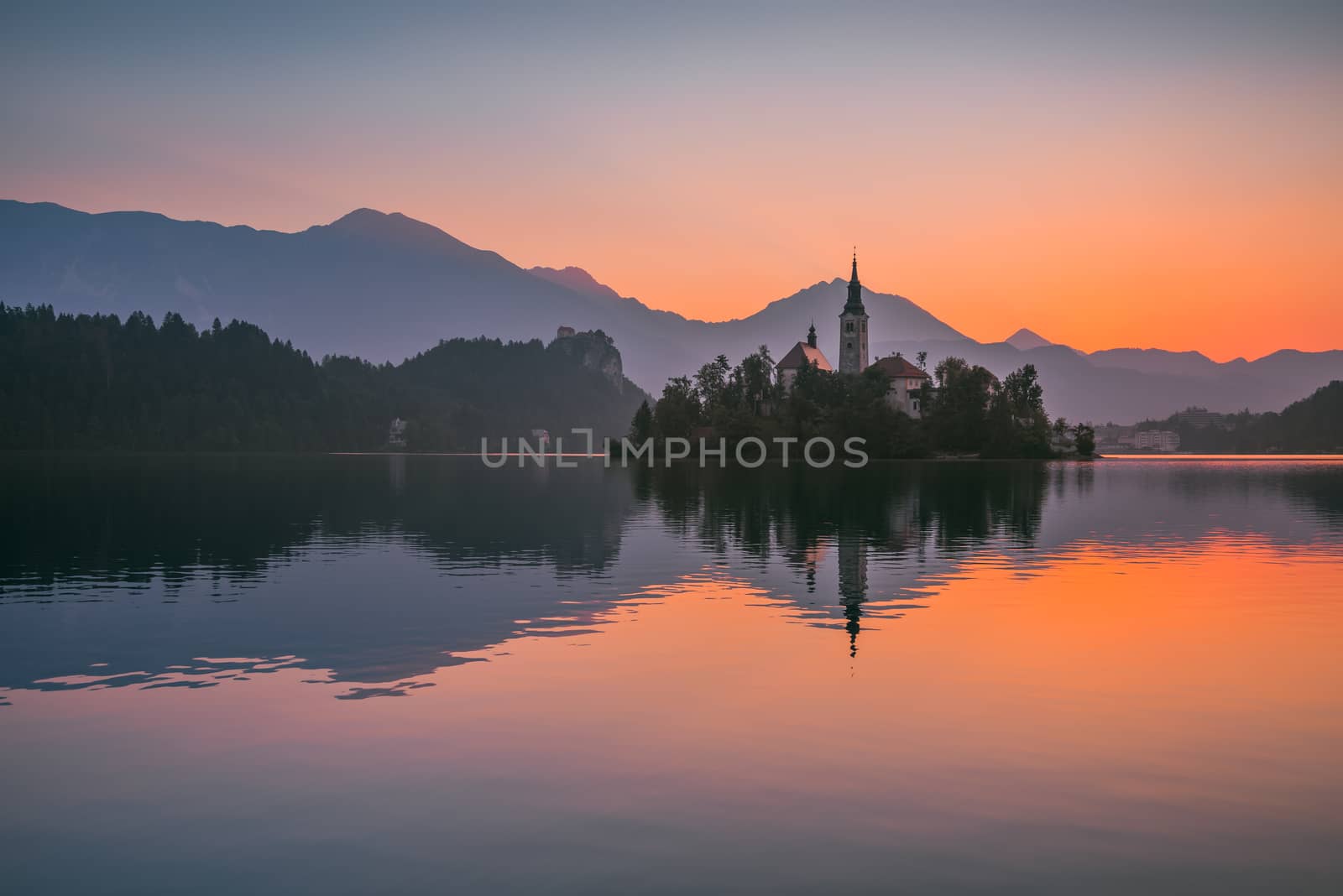 Little Island with Catholic Church in Bled Lake, Slovenia at Sunrise with Castle and Mountains in Background