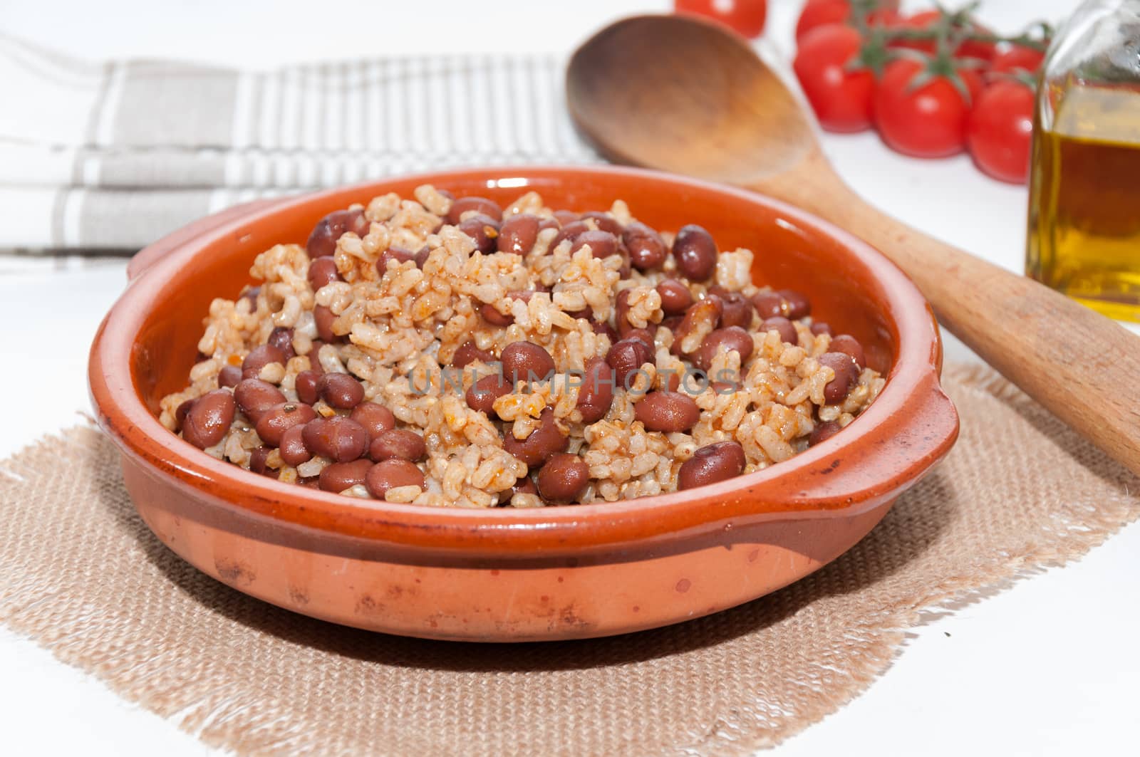 Casserole of beans with rice and various ingredients on a tablecloth raffia