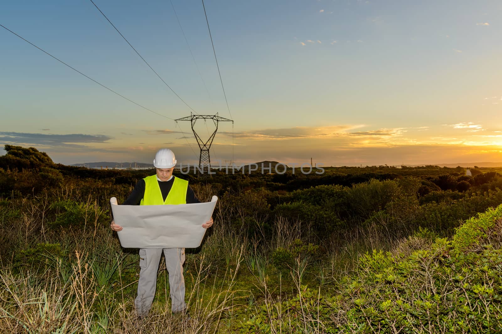 Electrical Engineer, Controls Power Line and wind turbines at sunset outdoors in the countryside