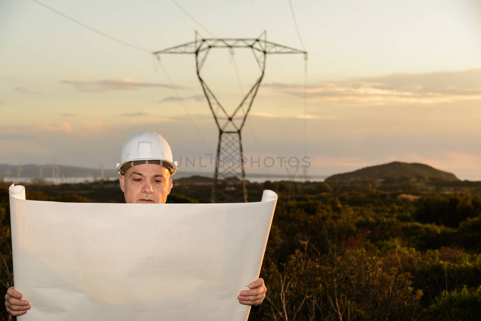Electrical Engineer, Controls Power Line and wind turbines at sunset outdoors in the countryside