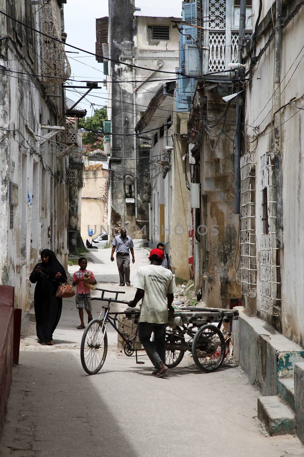 Stone town, Tanzania - December 30, 2015: Stone Town. Woman in Zanzibar all have to wear black burka when they go outside, even girls have to wear scalf on their heads. It is a Muslim life stile. Streets of the town are always lively. 