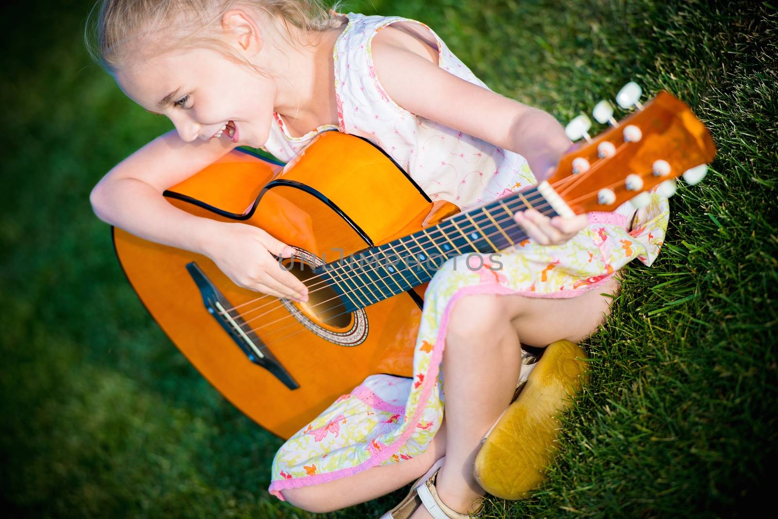 Little Guitar Player. Seven Years Old Girl Playing Guitar and Singing Some Song.