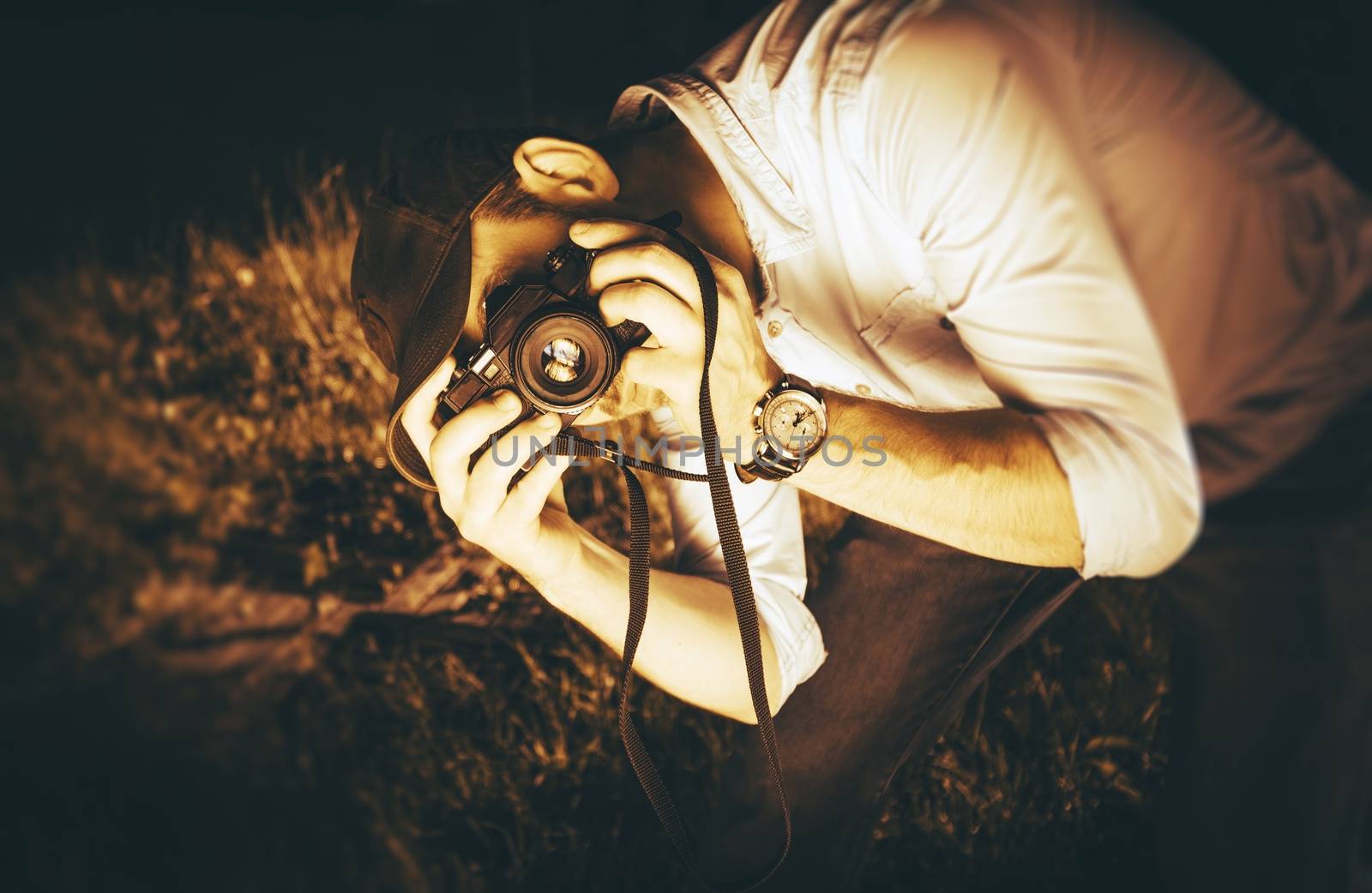 Photographer in Action. Caucasian Male Taking Pictures Using Vintage Analog Camera. Sepia Color Grading Photography Concept.