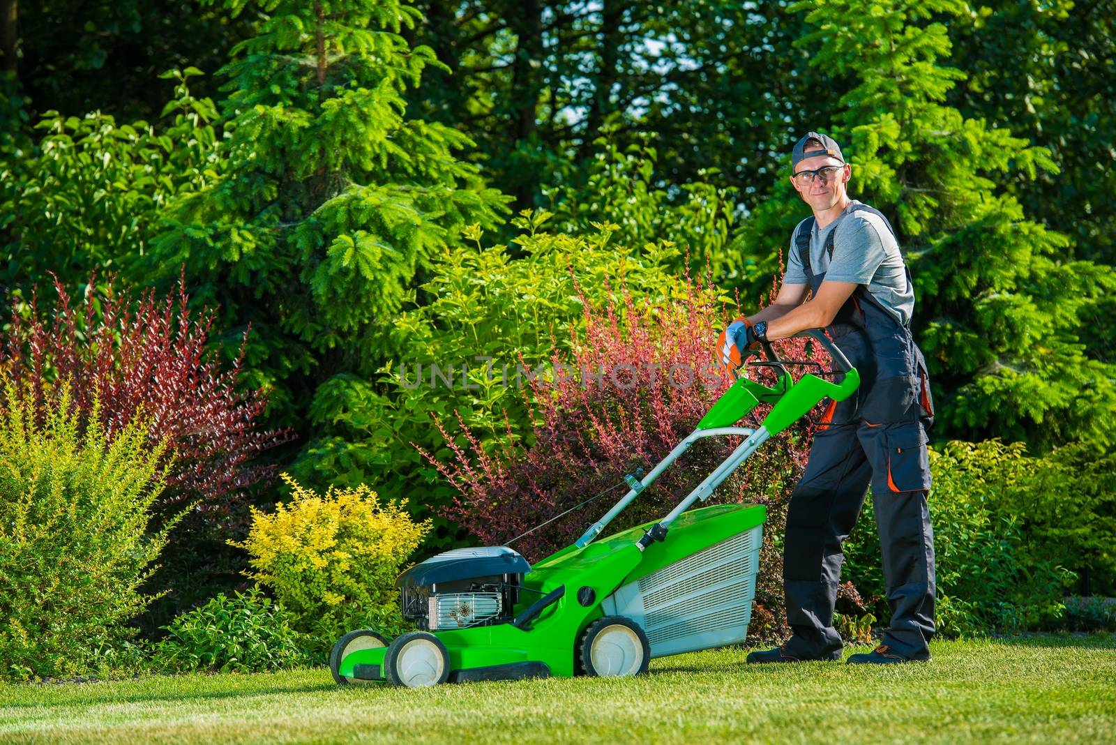 Smiling Professional Gardener with His Gasoline Lawn Mower. Professional Summer Landscaping Works