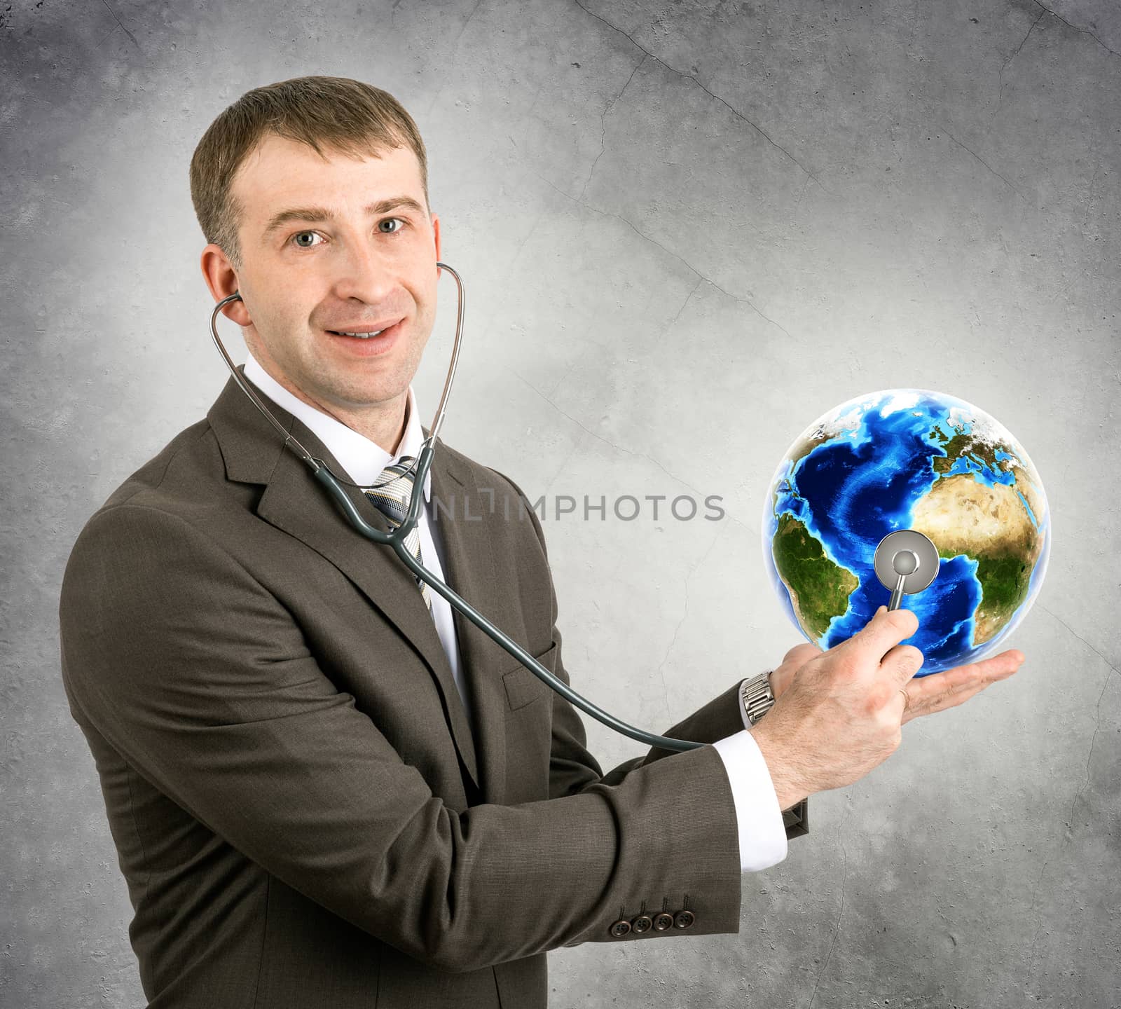Businessman with stethoscope hearing earth globe on his hand