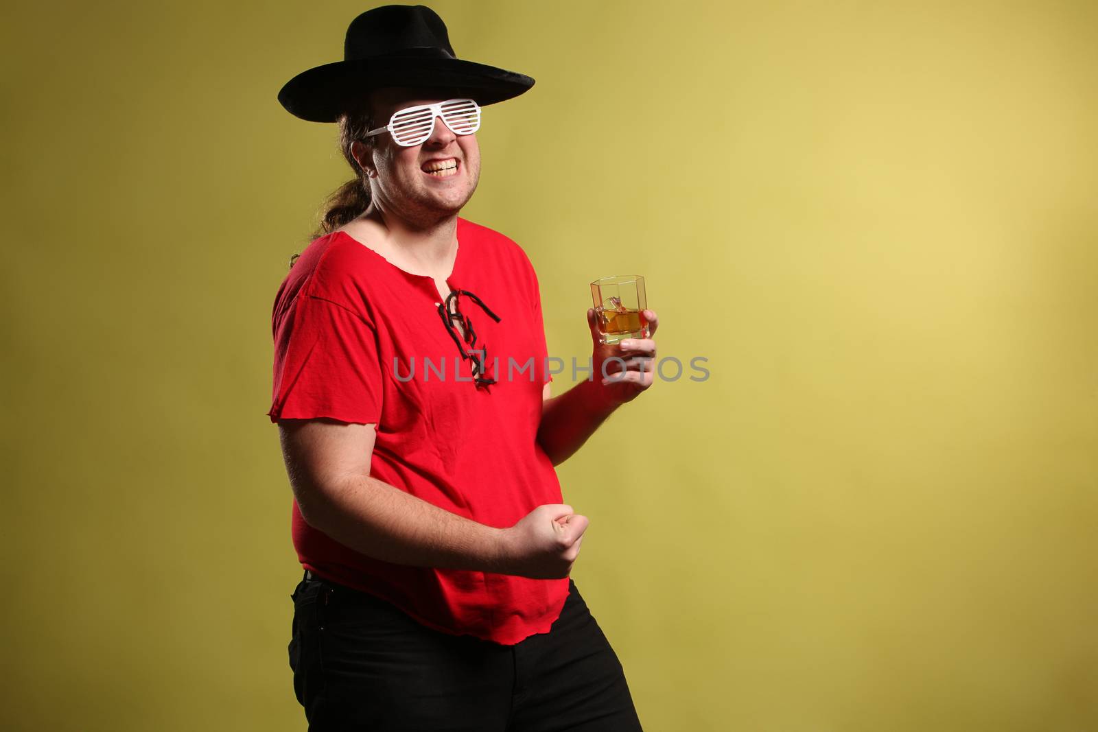 Crazy rock and rollerer with a big black hat, party glasses and a glass of whiskey in front of a cheetah skin background