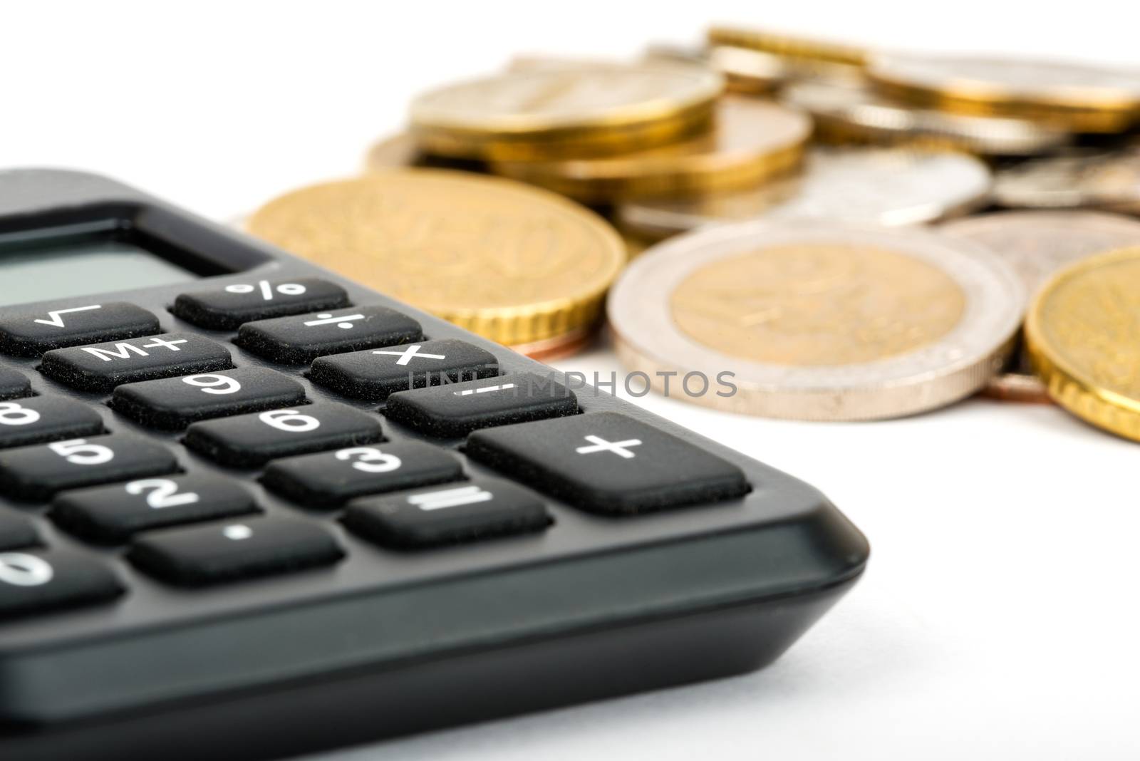 Calculator with stack of coins isolated on white background