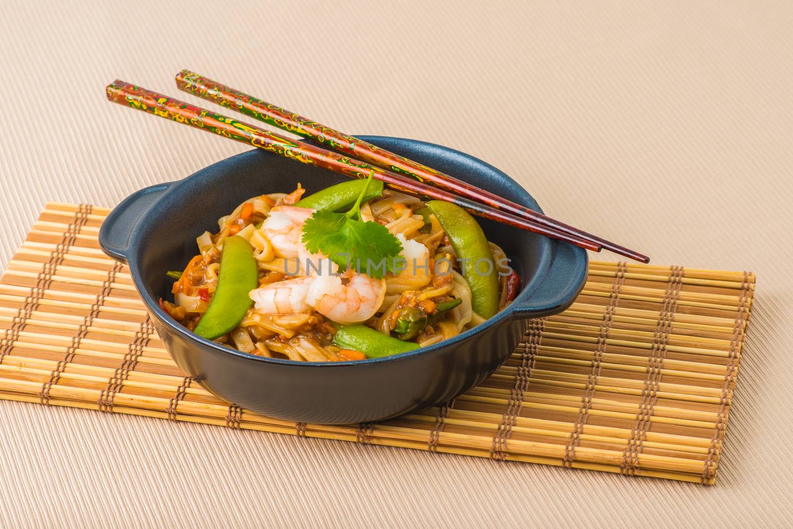 Serving of shrimp pad thai on a bamboo mat.