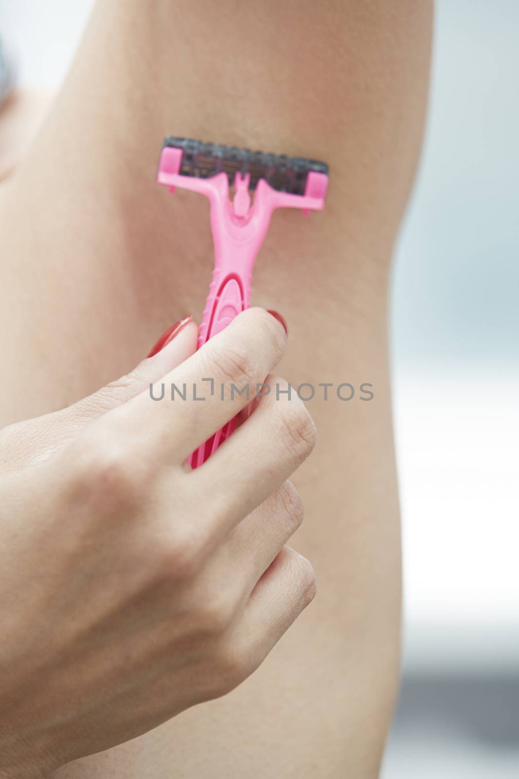 Woman shaving armpit. Close-up vertical photo