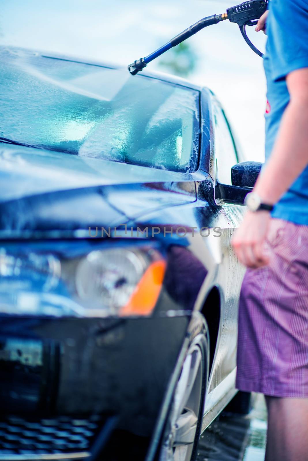 Self Service Car Wash. Young Men Cleaning His Car Using High Pressure Water.