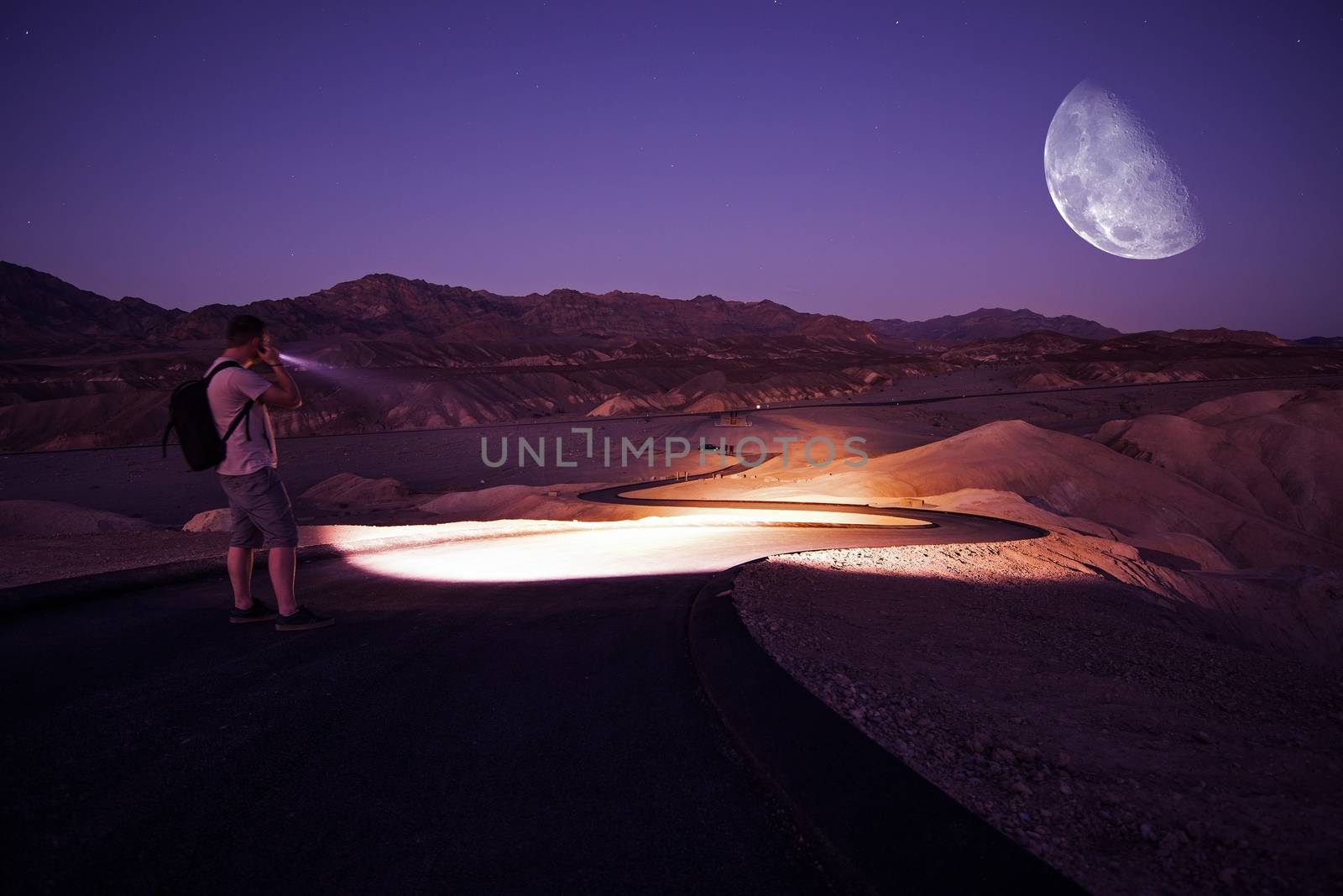 Hiker with Powerful Flashlight on Death Valley Trail During Starry Night. Night in Death Valley National Park, California, United States.