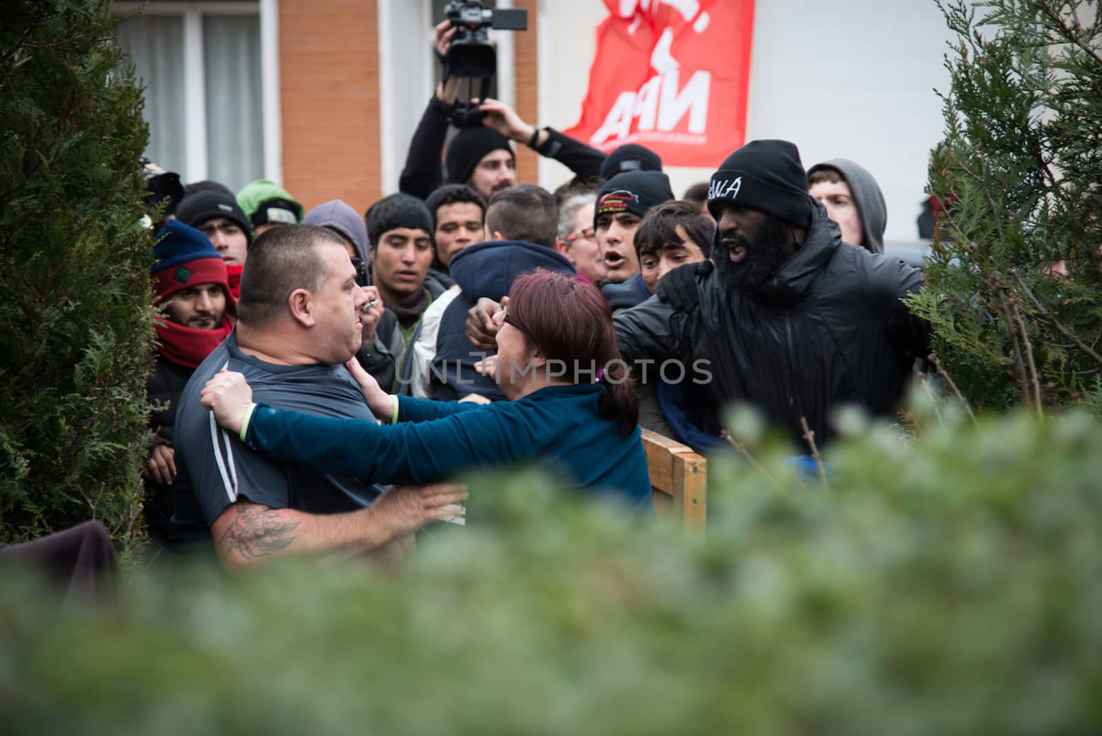 FRANCE, Calais: A woman holds a man who wants to fight with demonstrators in Calais on January 23, 2015 as a demonstration supporting migrants and refugees passes by their house. 
