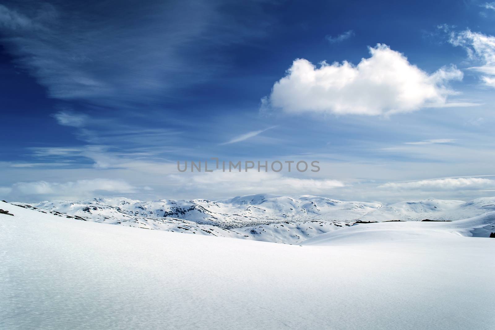 Winter view on mountain range. Pure white snow field. Blue sky, white cloud. Norway.