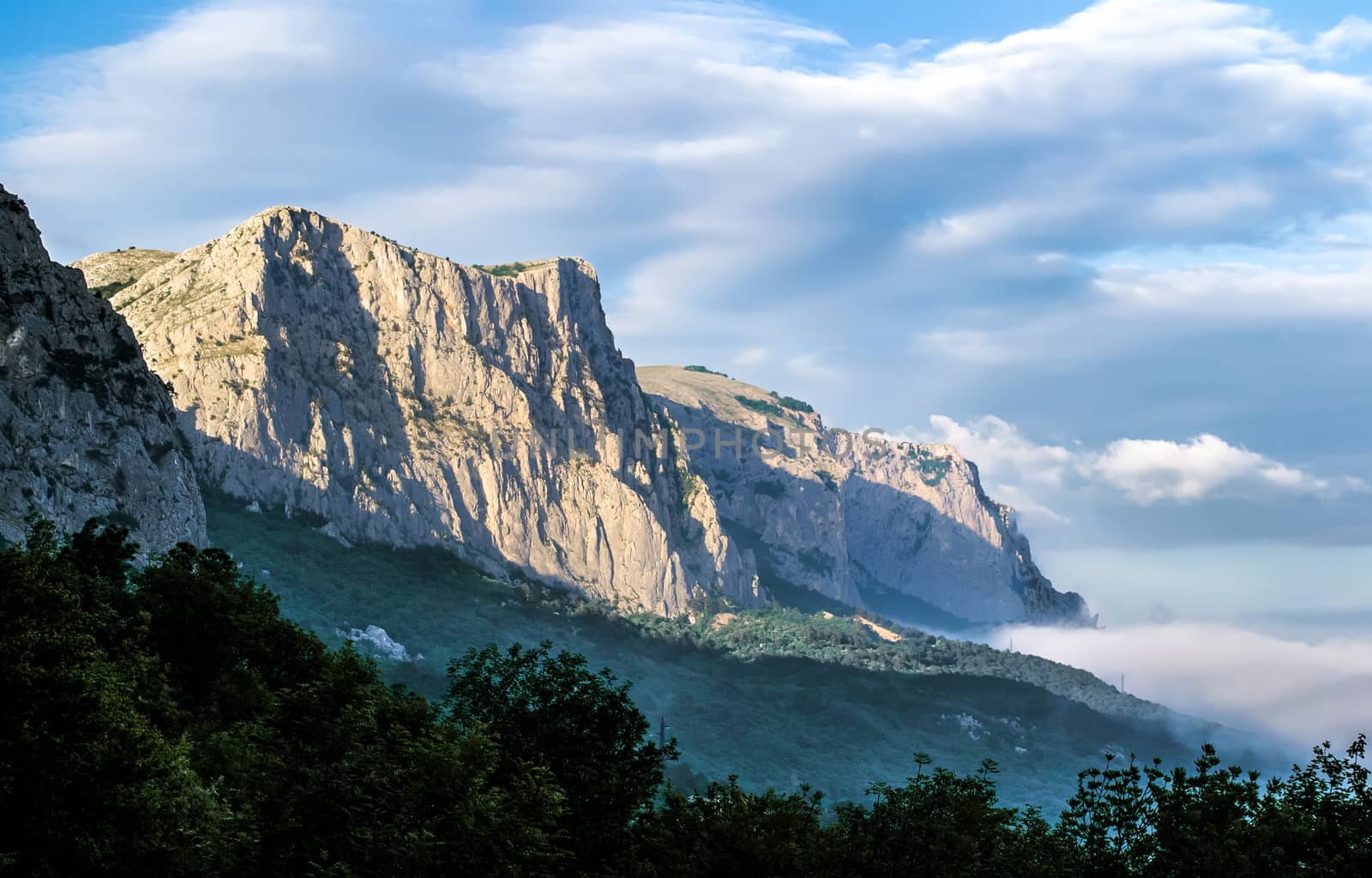 Crimean rocks in the light of the evening sun. Trees in the foreground.