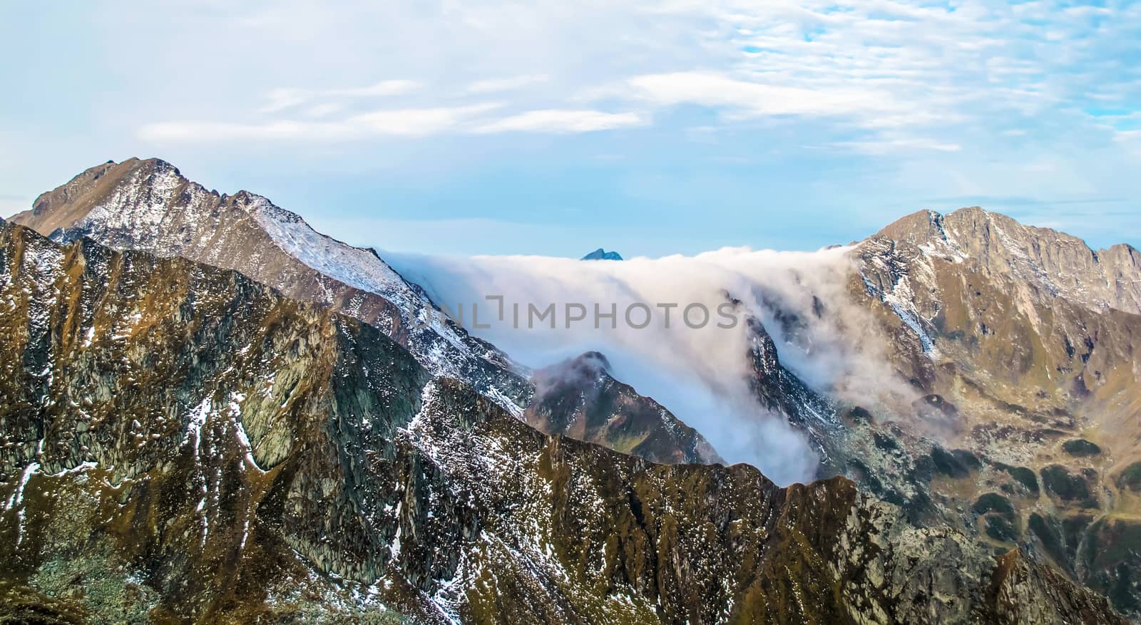 Morning fog crawling over rocky mountain ridge. Romania. Carpathian