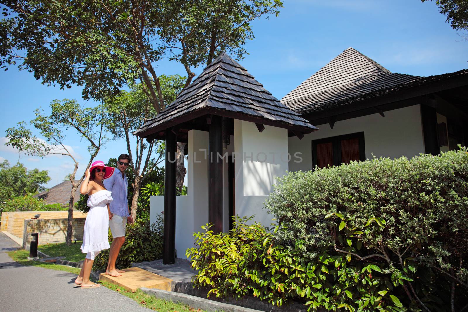 Young attractive couple standing by their villa 