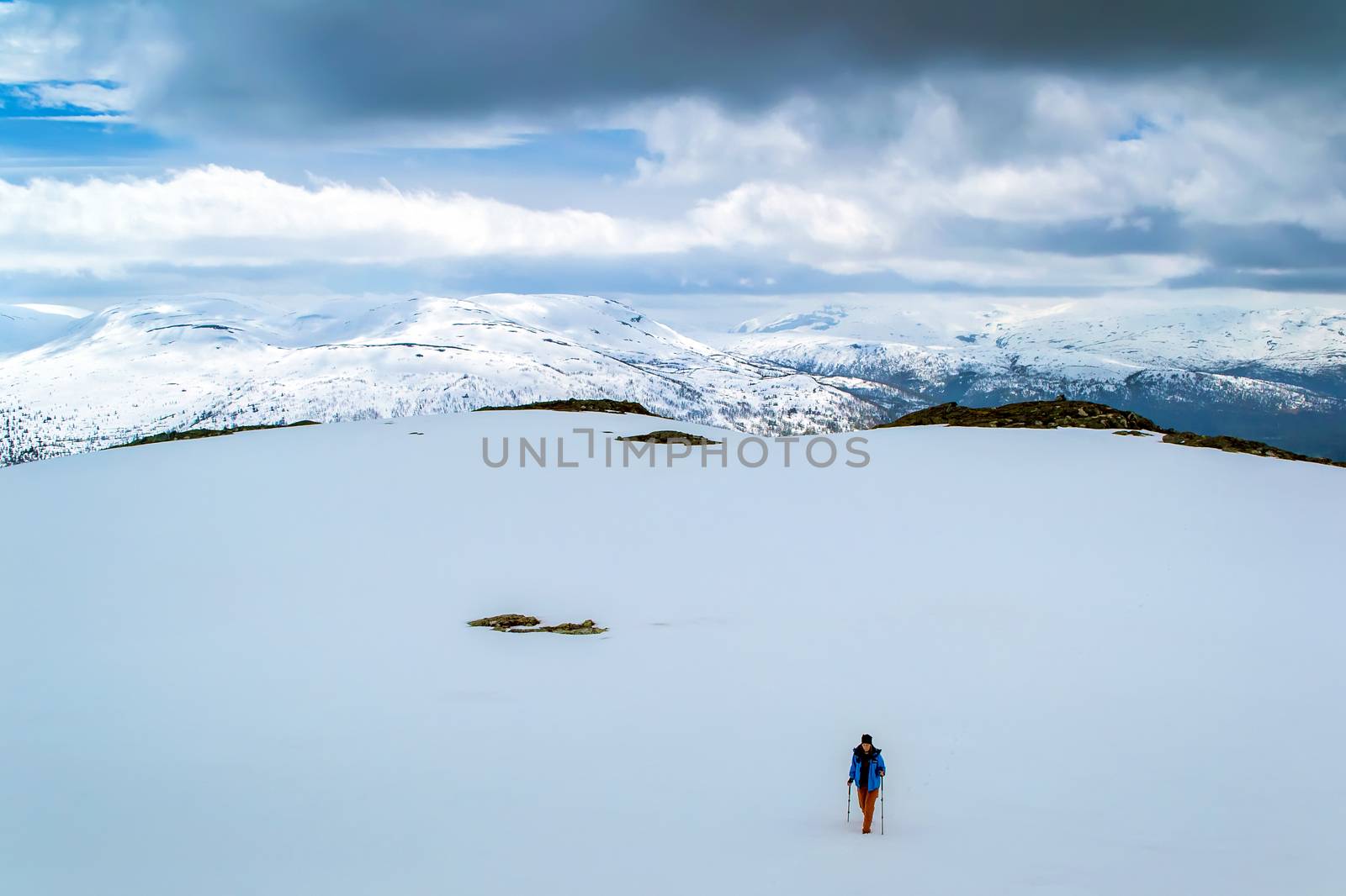 Tourist on snow field. Trekking in the snowy winter mountains. Clouds. Norway