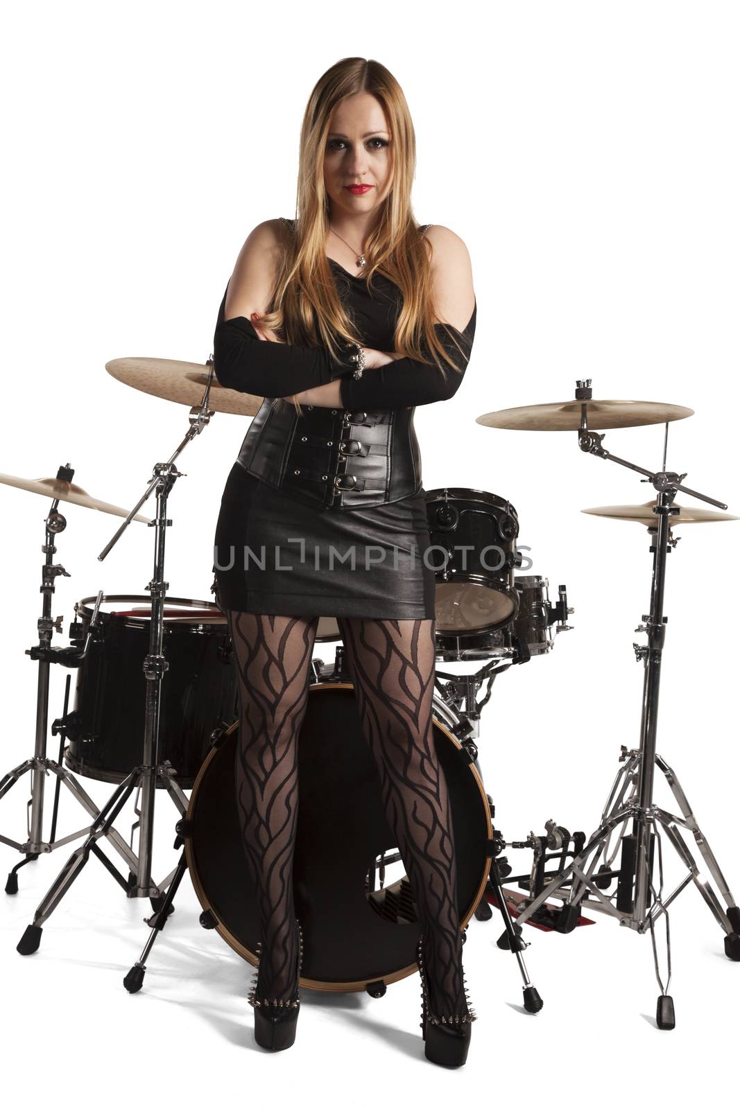 Young woman standing in front of drumkit on white background