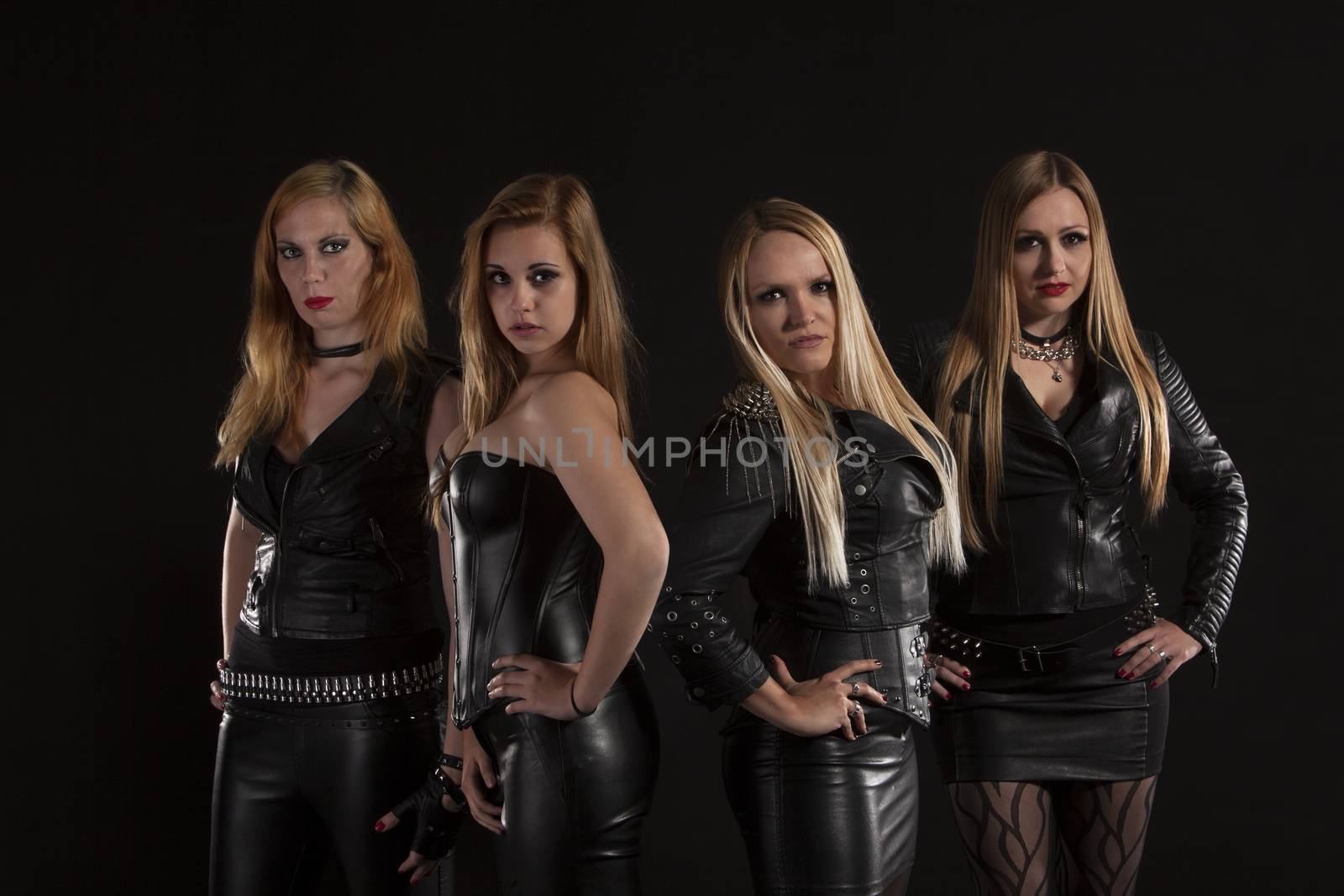 Group of young women wearing leather outfits on black background