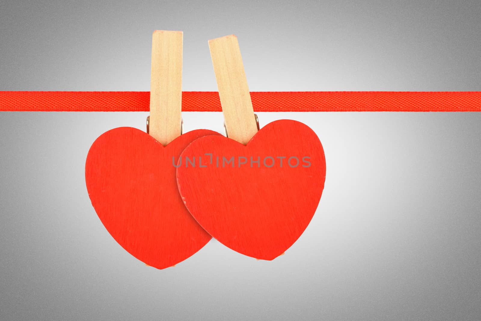 Valentine day template, two red wooden hearts with clothes pins on textile ribbon over grayscale grain noise gradient