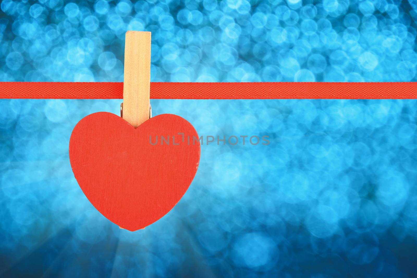 Valentine day template, one red wooden heart with clothes pin on textile ribbon over winter snow blue glitter blur