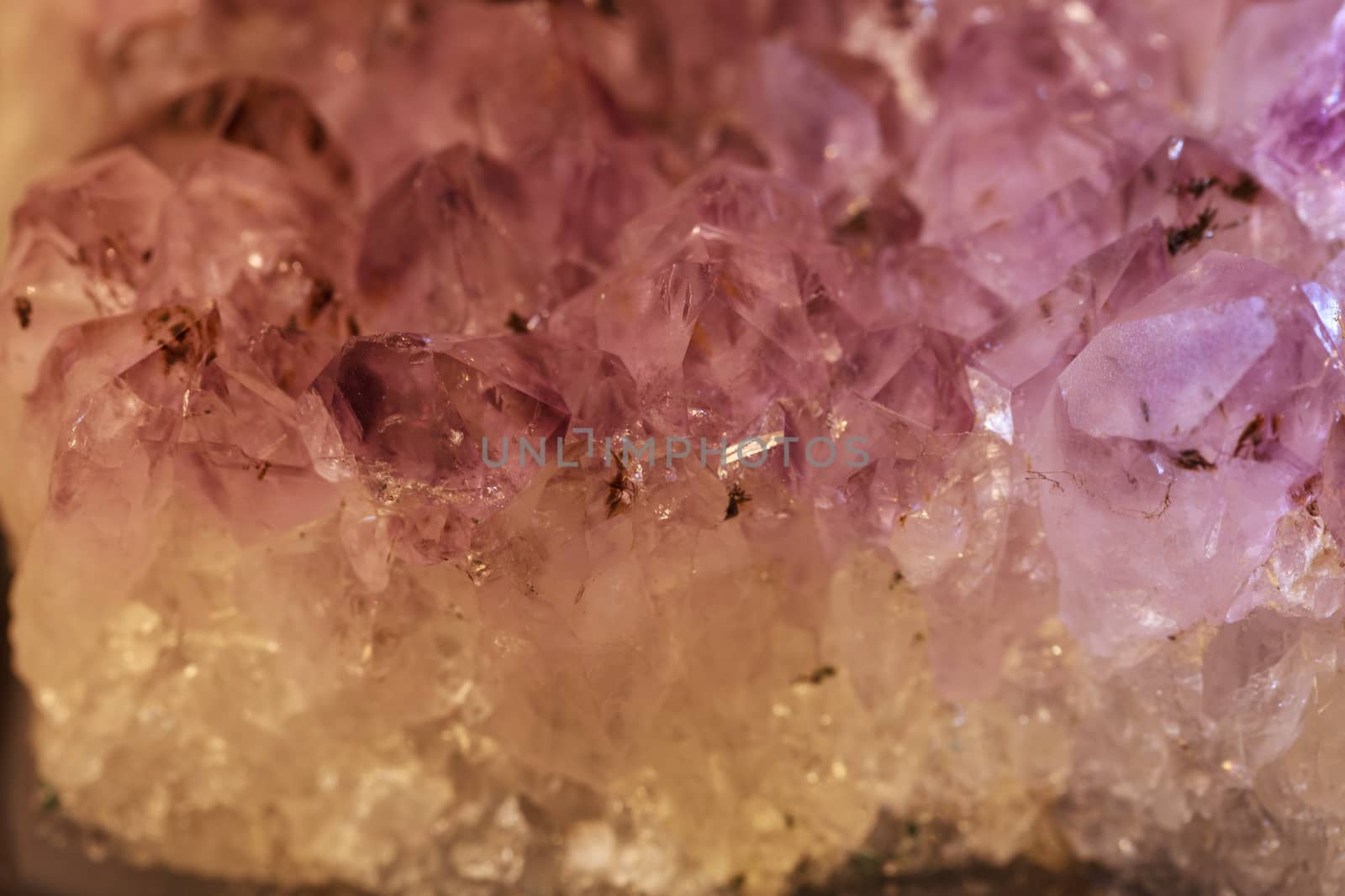 Purple and white natural amethyst geode background pattern glitters in the light.