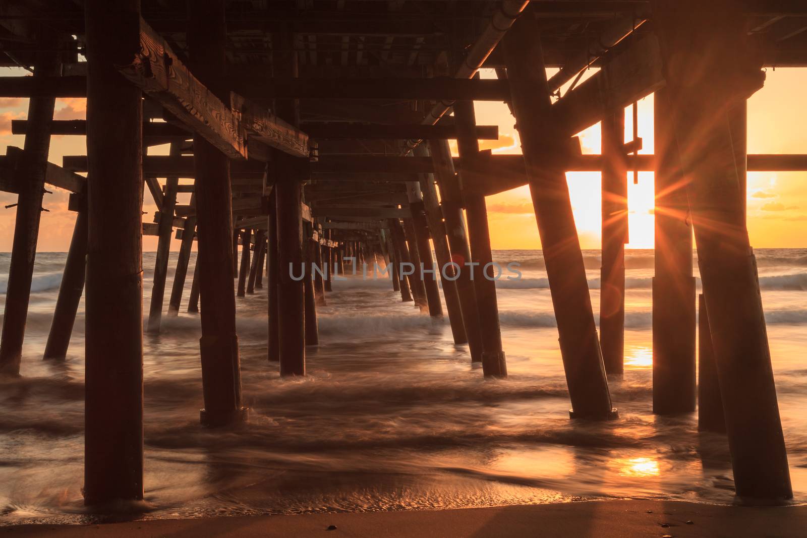 Under the San Clemente pier on the beach at sunset in the fall in Southern California, United States.