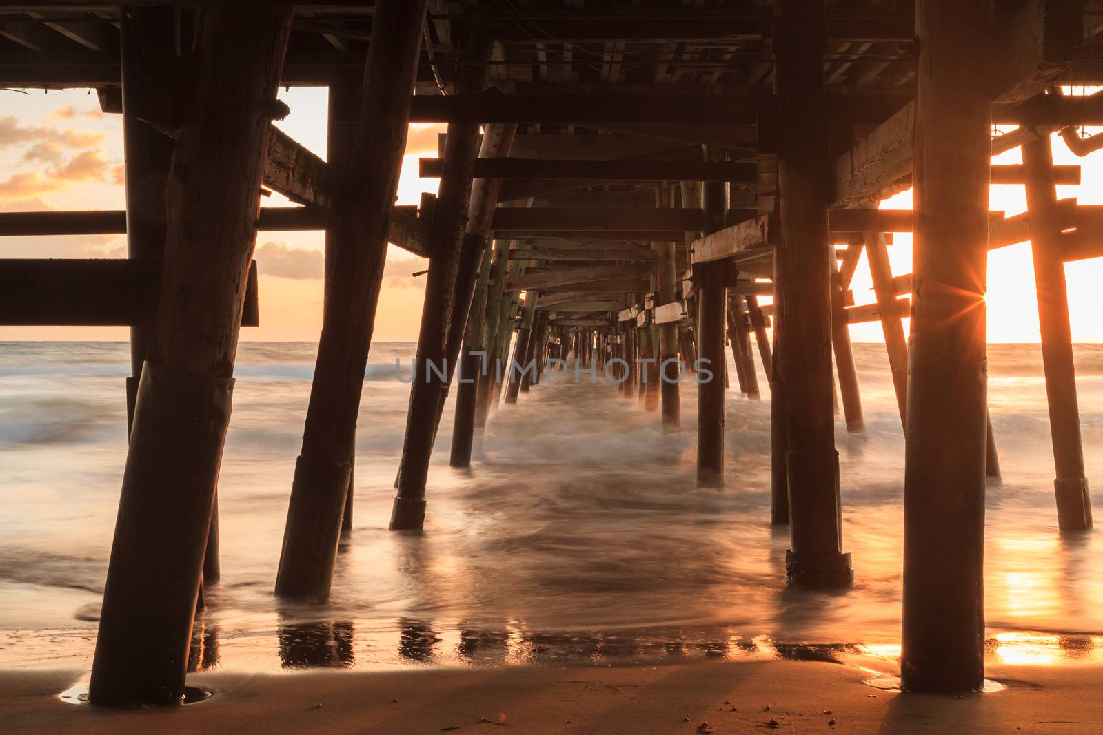 Under the San Clemente pier on the beach at sunset in the fall in Southern California, United States.