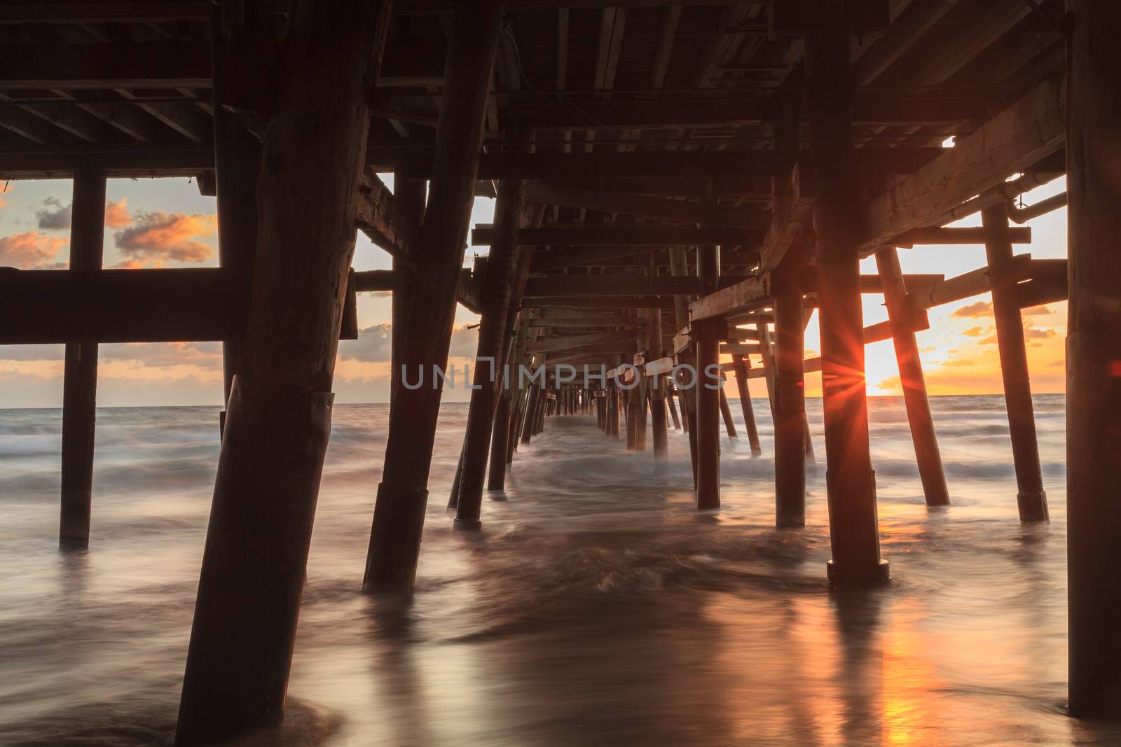 Under the San Clemente pier on the beach at sunset in the fall in Southern California, United States.