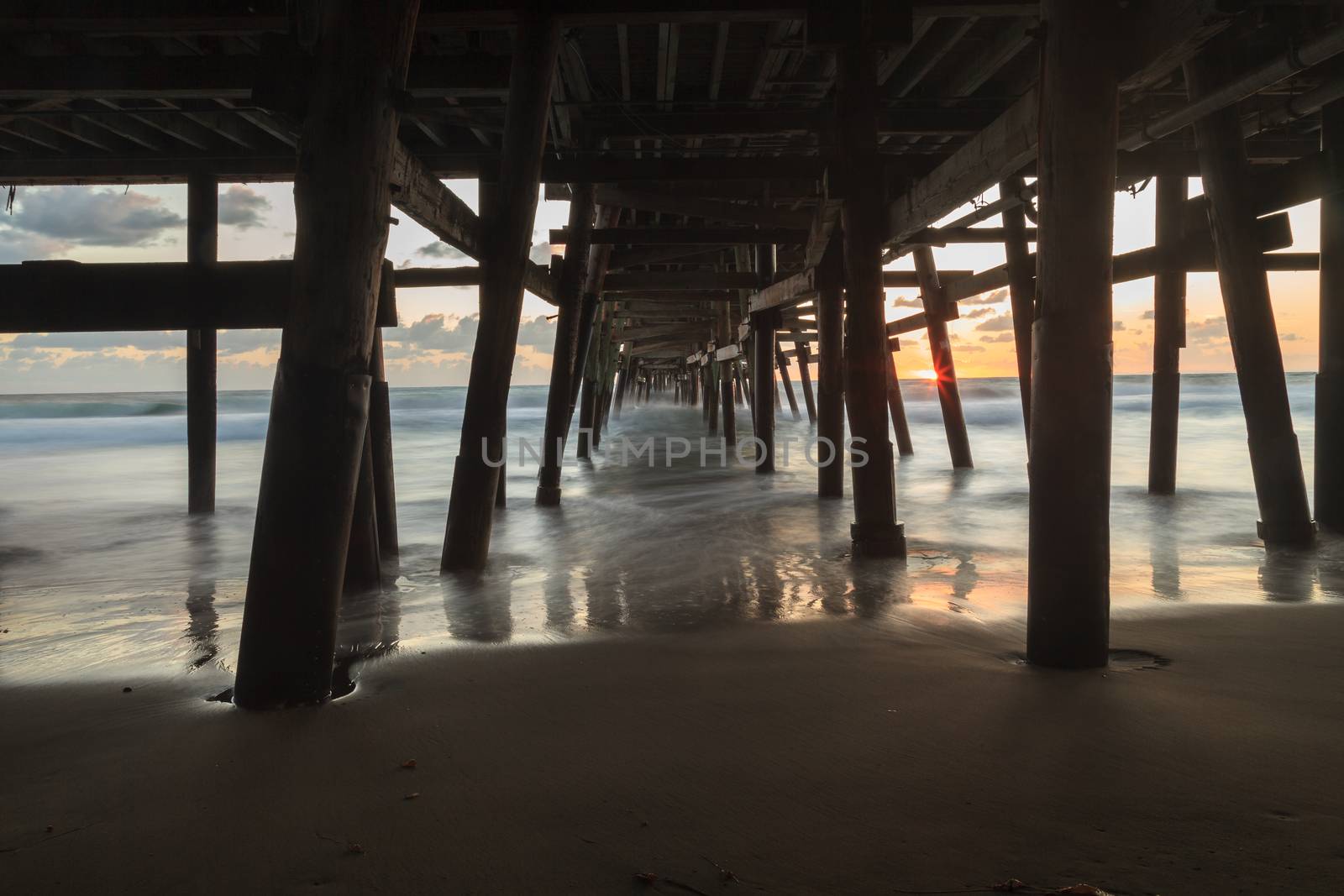 Under the San Clemente pier on the beach at sunset in the fall in Southern California, United States.