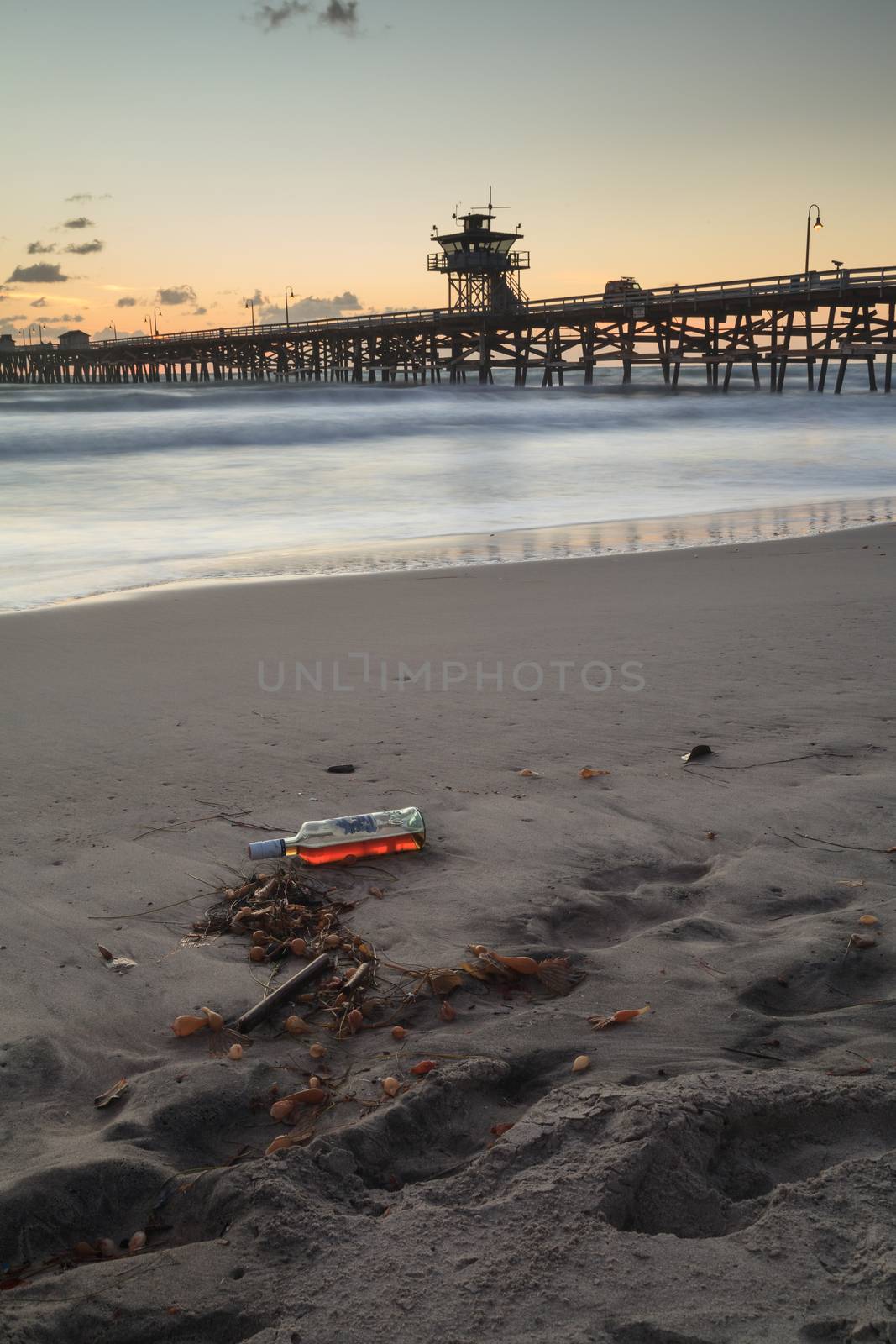 Bottle of alcohol on the beach in front of the San Clemente pier at sunset in San Clemente, Southern California, United States