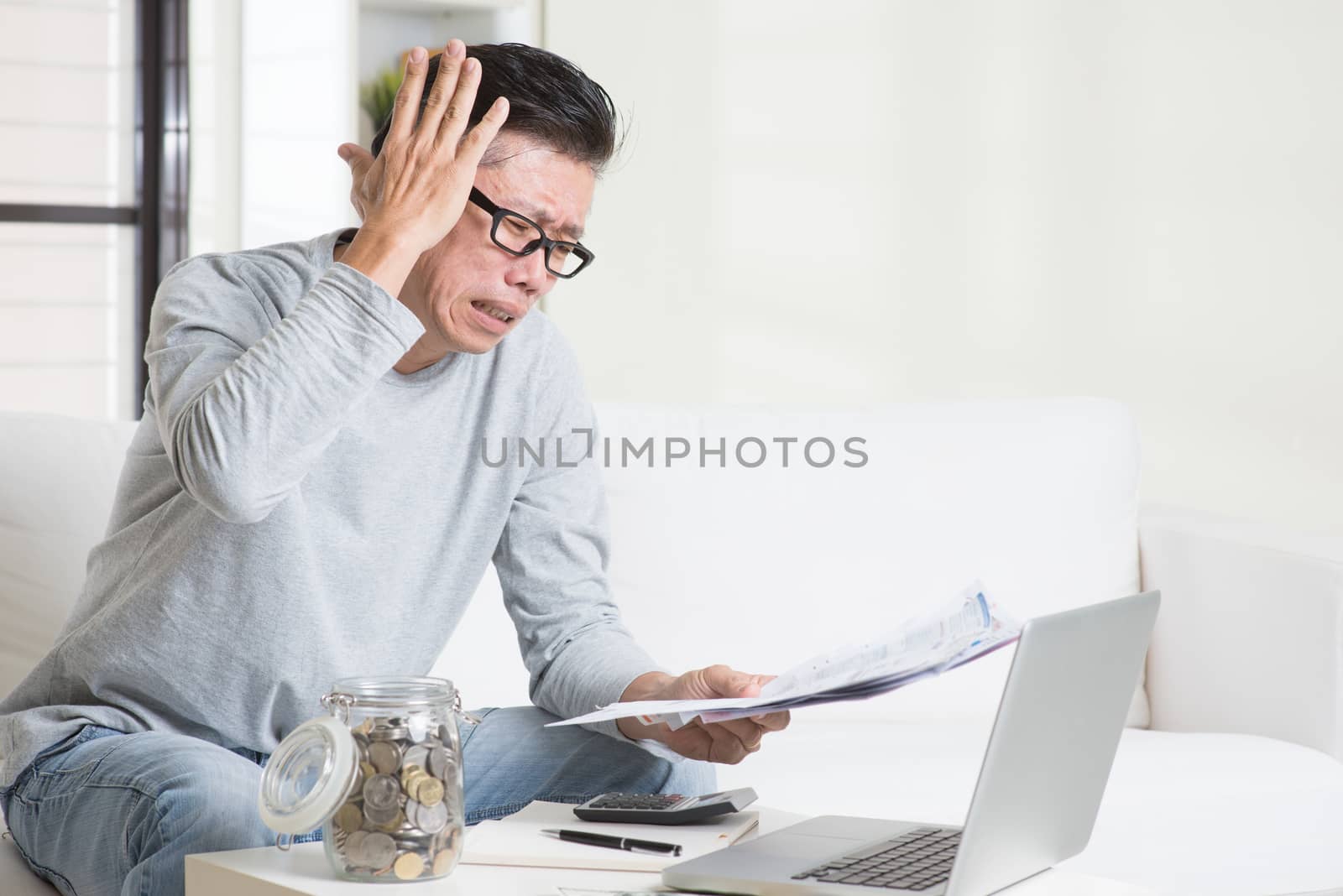 Portrait of 50s mature Asian man having a hard time paying bills. Saving, retirement, retirees financial planning concept. Family living lifestyle at home.